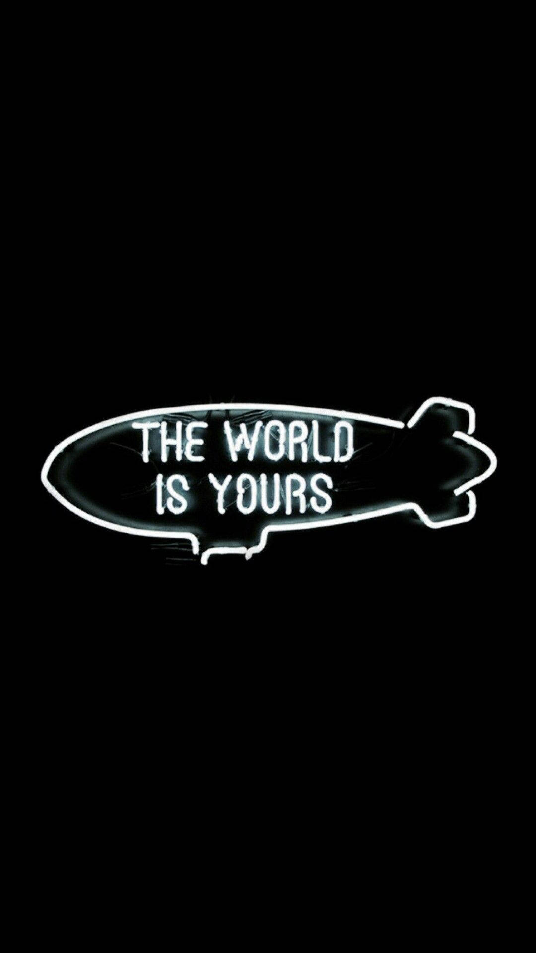 The World Is Yours 桌布 壁紙 — 一個發光的白色霓虹燈牌，形狀像飛船，在純黑色背景上寫著「THE WORLD IS YOURS」。