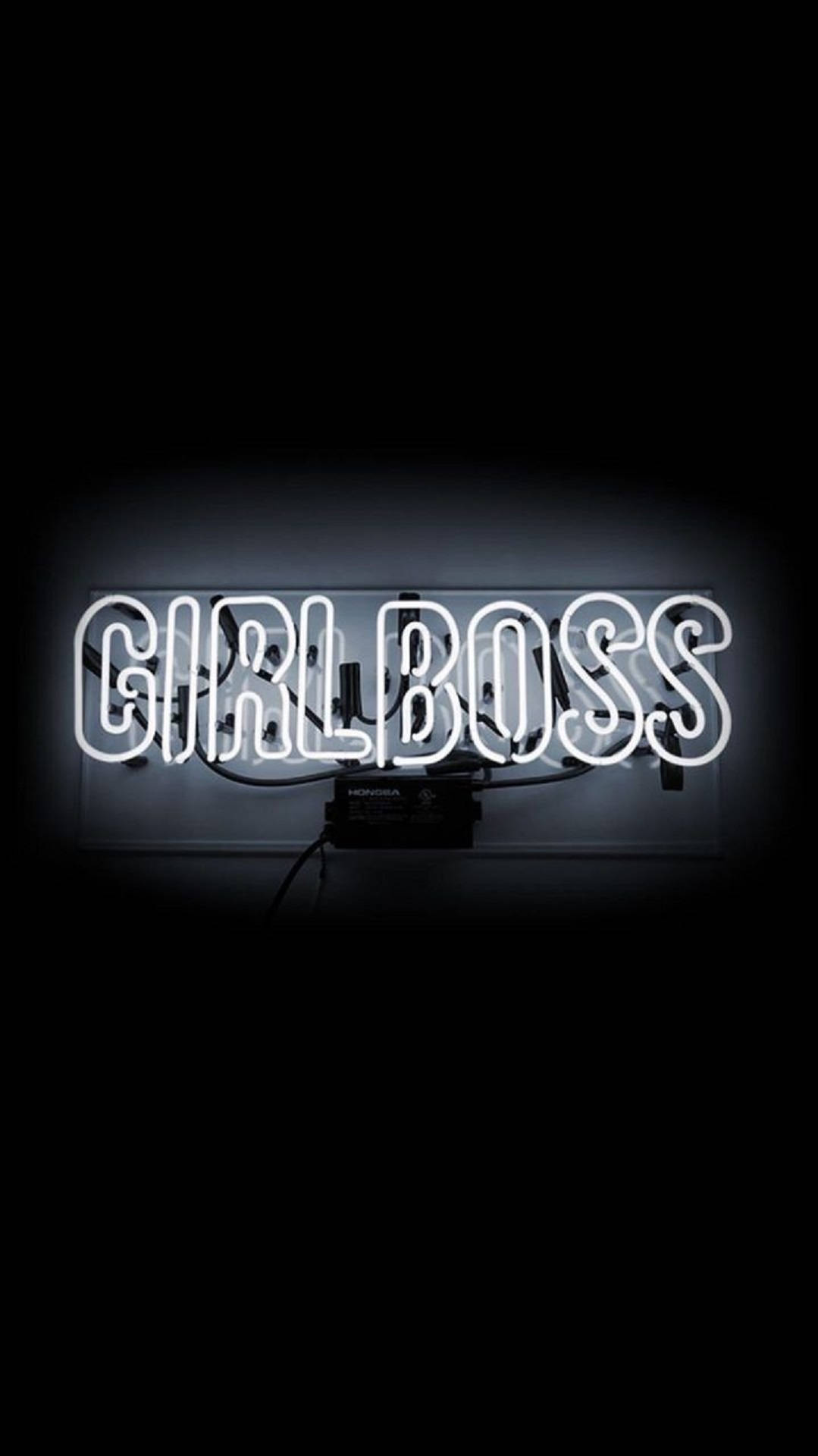 boss 桌布 壁紙 — 一個發光的白色霓虹燈牌，拼寫著「GIRLBOSS」，以柔和的光暈效果照亮黑暗的房間。