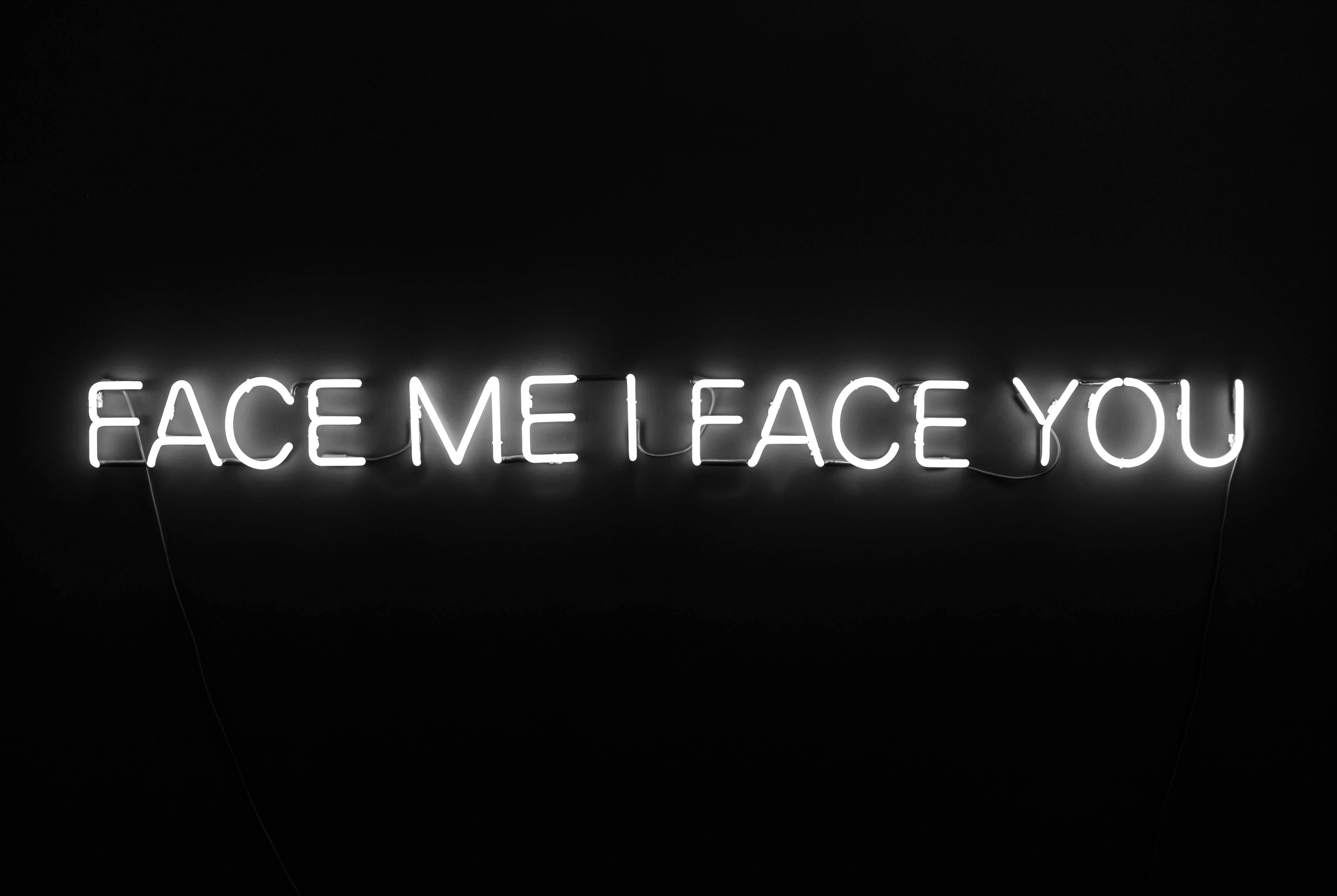 Word 桌布 壁紙 — 一個發光的白色霓虹燈牌在漆黑牆上顯示 face me i face you。