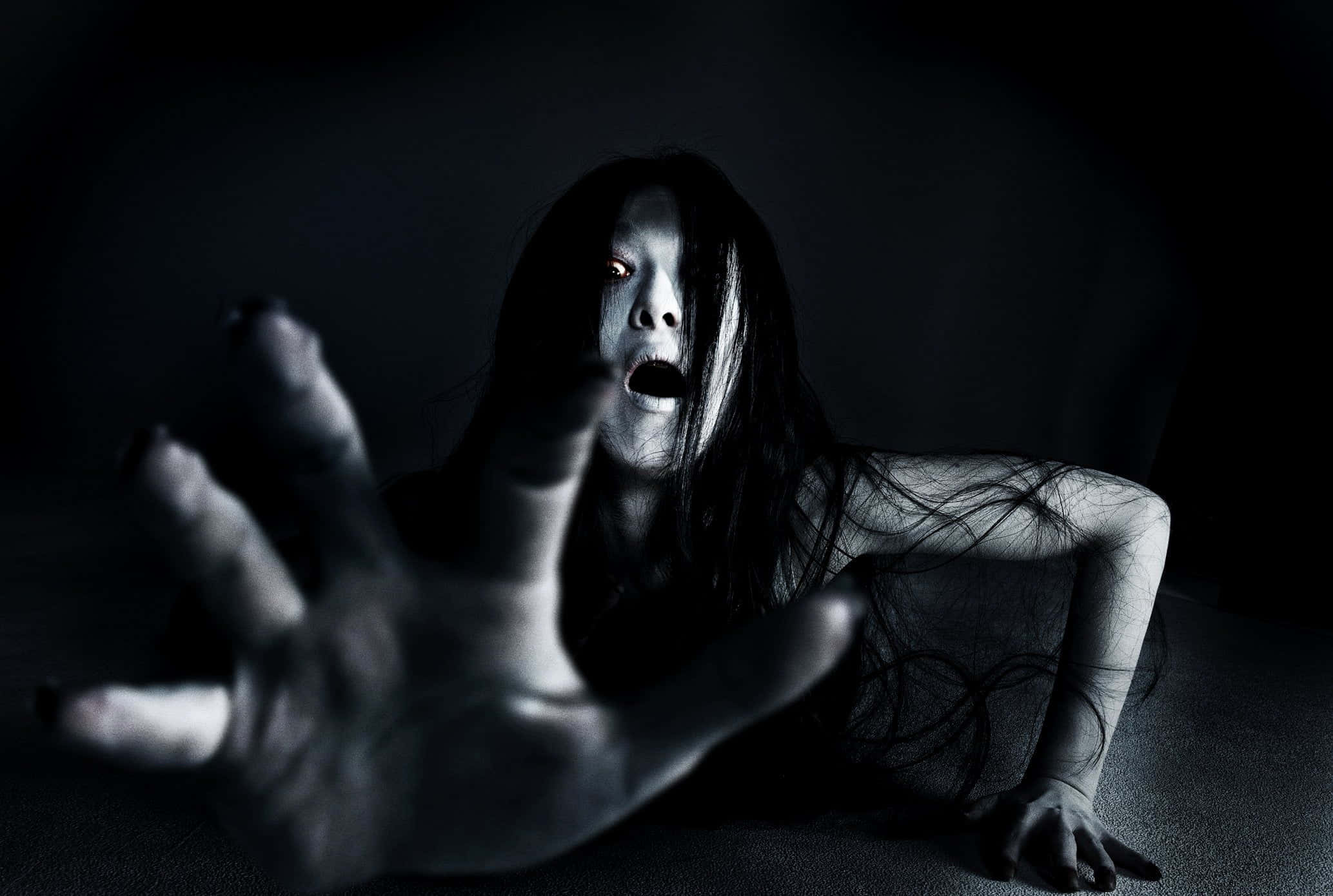 Dark Fear 桌布 壁紙 — 一個發光的眼睛和伸出雙手的鬼影從黑暗中出現，營造出令人毛骨悚然的恐怖場景。