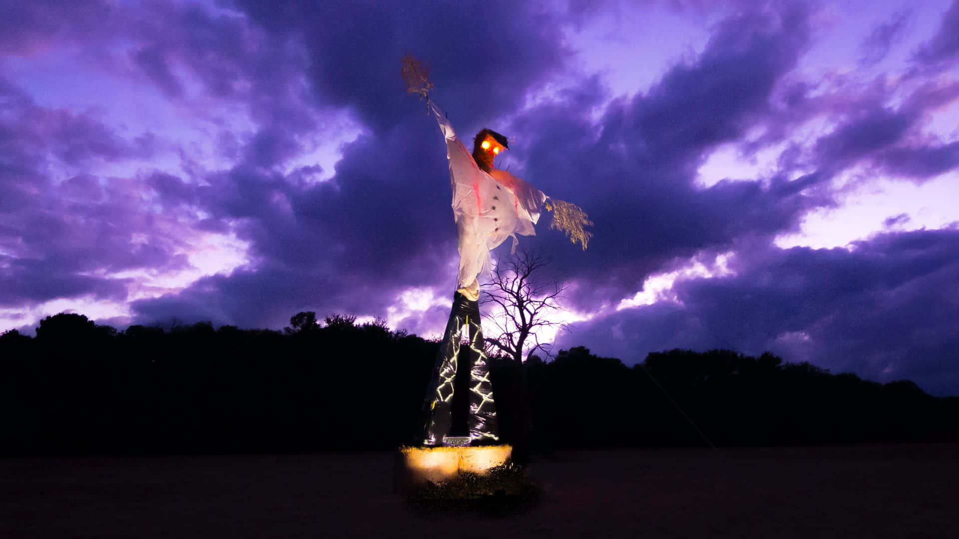 Scarecrows 桌布 壁紙 — 一個發光的稻草人穿著白色西裝，在帶有烏雲的戲劇性紫色暮色天空下高高聳立。