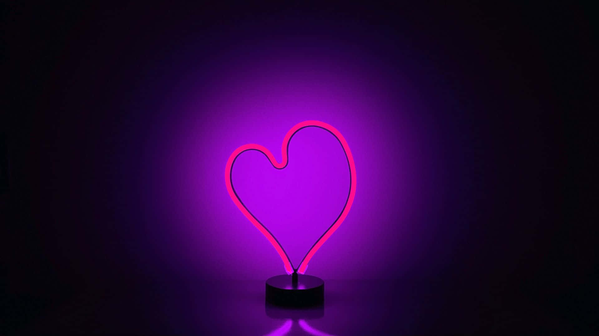 Purple Heart 桌布 壁紙 — 一個發光的粉紅色霓虹心形燈在黑暗背景下投射出柔和的紫色光暈。