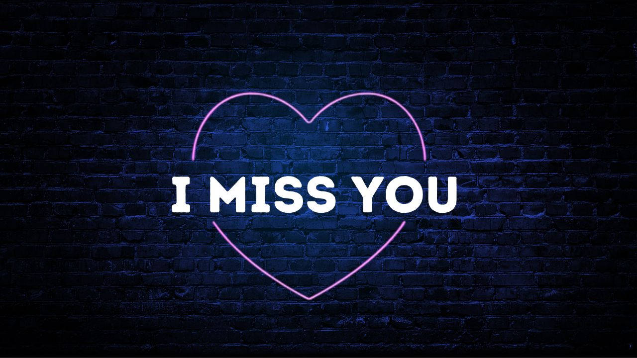 I Miss You 桌布 壁紙 — 一個發光的粉紅色霓虹心形輪廓，帶有白色文字 I MISS YOU，在深藍色磚牆上閃耀。