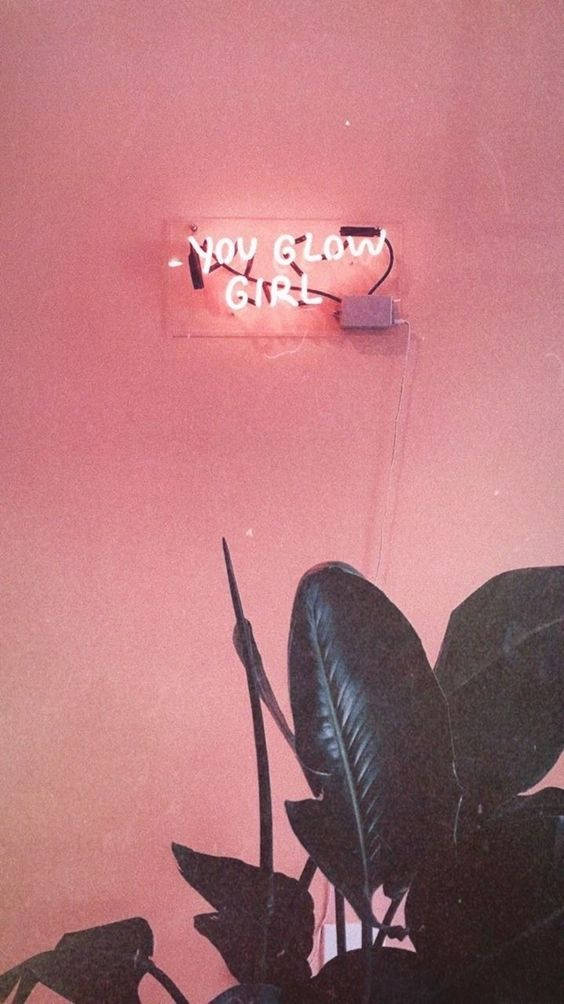 you go girl 桌布 壁紙 — 一個發光的粉紅色霓虹燈牌，上面寫著 you glow girl，安裝在相配的粉紅色牆壁上，位於深色葉子剪影上方。