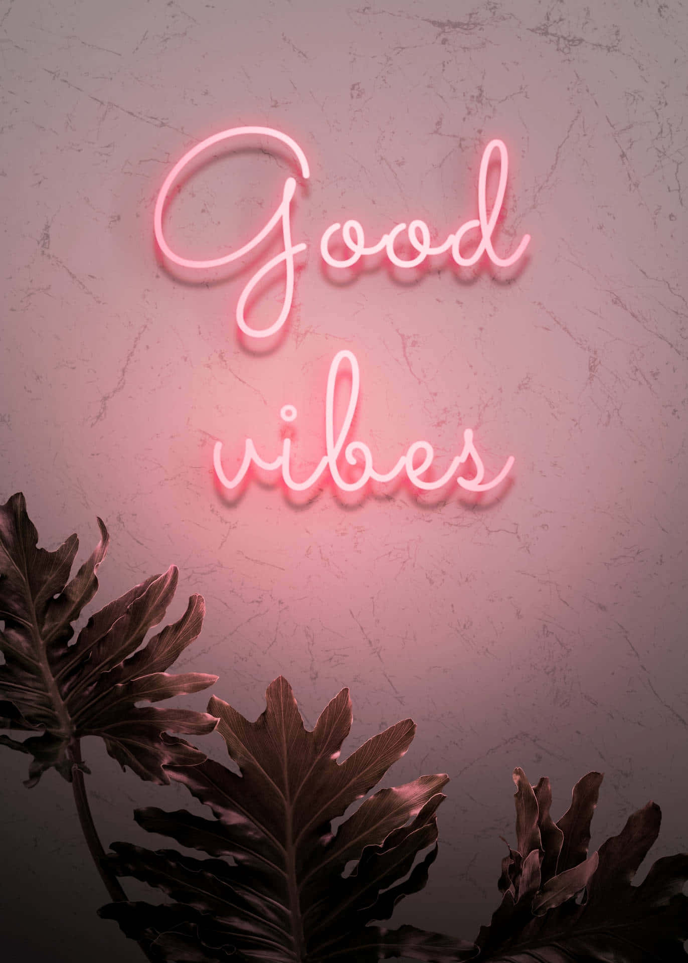 Neon Light 桌布 壁紙 — 一個發光的粉紅色霓虹燈牌，上面寫著「Good vibes」，在紋理牆壁上投射出柔和的光線，底部有深色熱帶葉子作為框架。