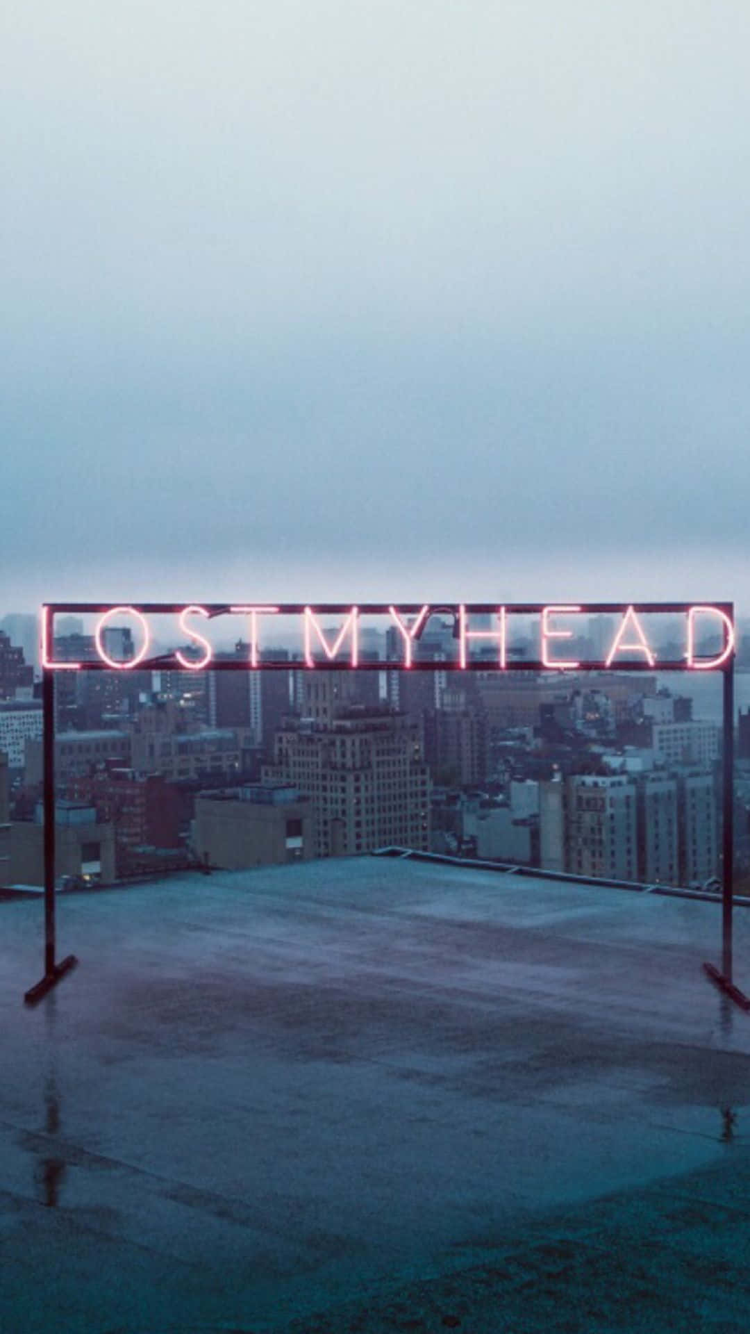 憂鬱美學 桌布 壁紙 — 一個發光的粉紅色霓虹燈牌，上面寫著 lostmyhead，矗立在一個濕漉漉的屋頂上，俯瞰著黃昏時分朦朧的城市景觀。