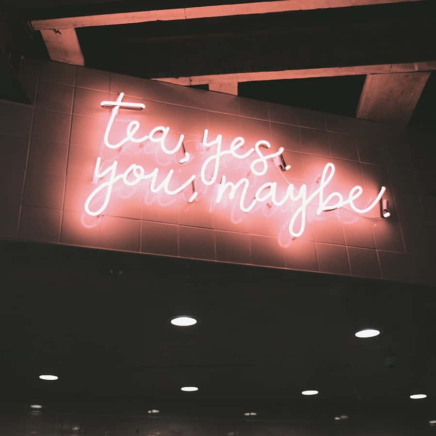 Aesthetic Grunge Neon Signs 桌布 壁紙 — 一個發光的粉紅色霓虹燈牌，上面寫著 tea yes you maybe，在裸露的木樑下為瓷磚牆壁投下溫暖的光芒。