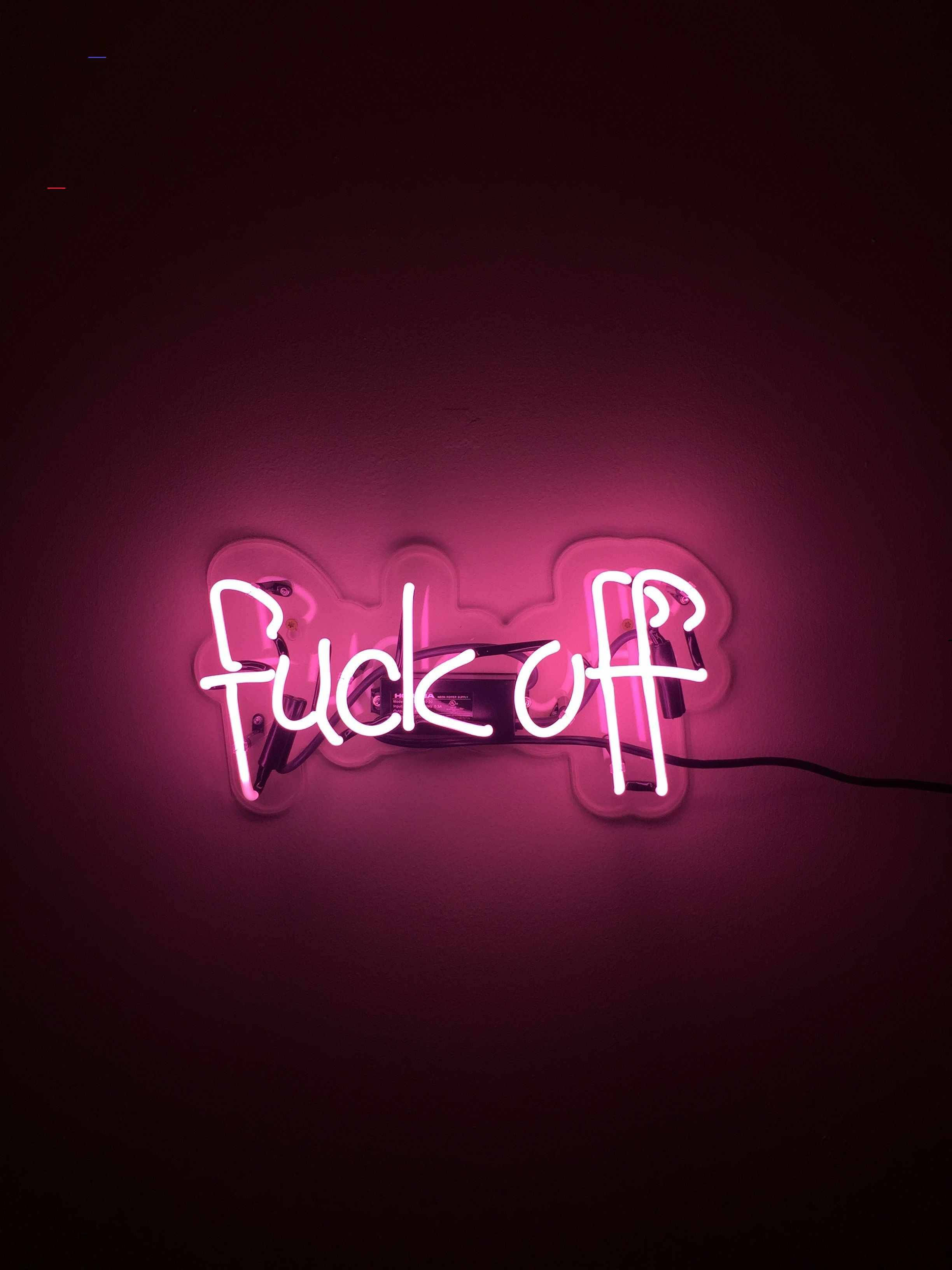 壞女孩 桌布 壁紙 — 一個發光的粉紅色霓虹燈牌，上面寫著「fuck off」，在黑暗的牆壁上投射出鮮豔的光芒。