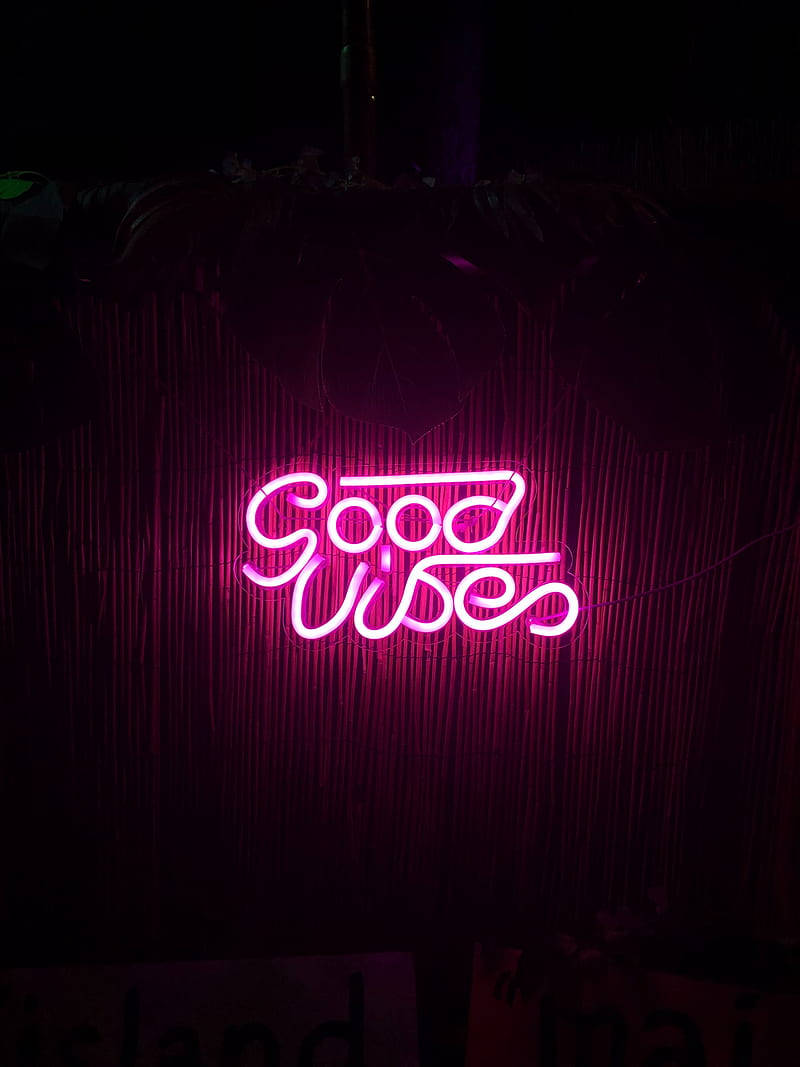 lights 桌布 壁紙 — 一個發光的粉紅色霓虹燈牌，上面寫著「Good Vibes」，在夜晚照亮了深色的竹簾。