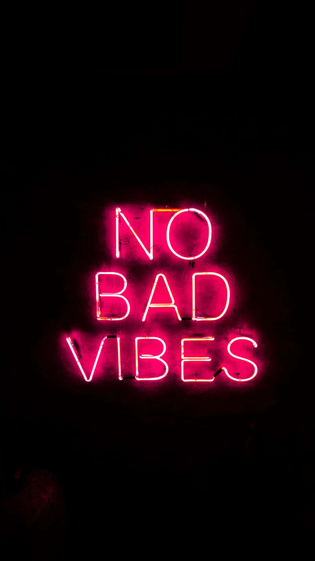 neon sign 桌布 壁紙 — 一個發光的粉紅色霓虹燈牌，上面寫著「NO BAD VIBES」，在漆黑的背景下明亮閃耀。