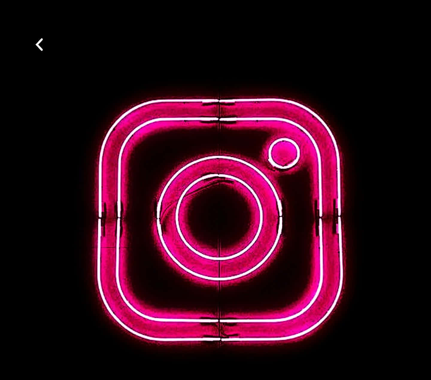Instagram Black Logo 桌布 壁紙 — 一個發光的粉紅色霓虹燈牌，形狀像Instagram標誌，在黑色背景上明亮地閃耀。
