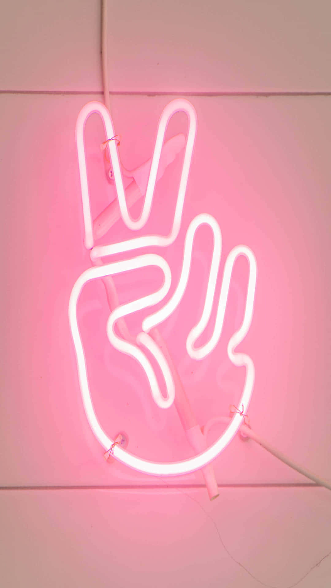 Neon Light 桌布 壁紙 — 一個發光的粉紅色霓虹燈牌，形狀為和平手勢，安裝在瓷磚牆上。