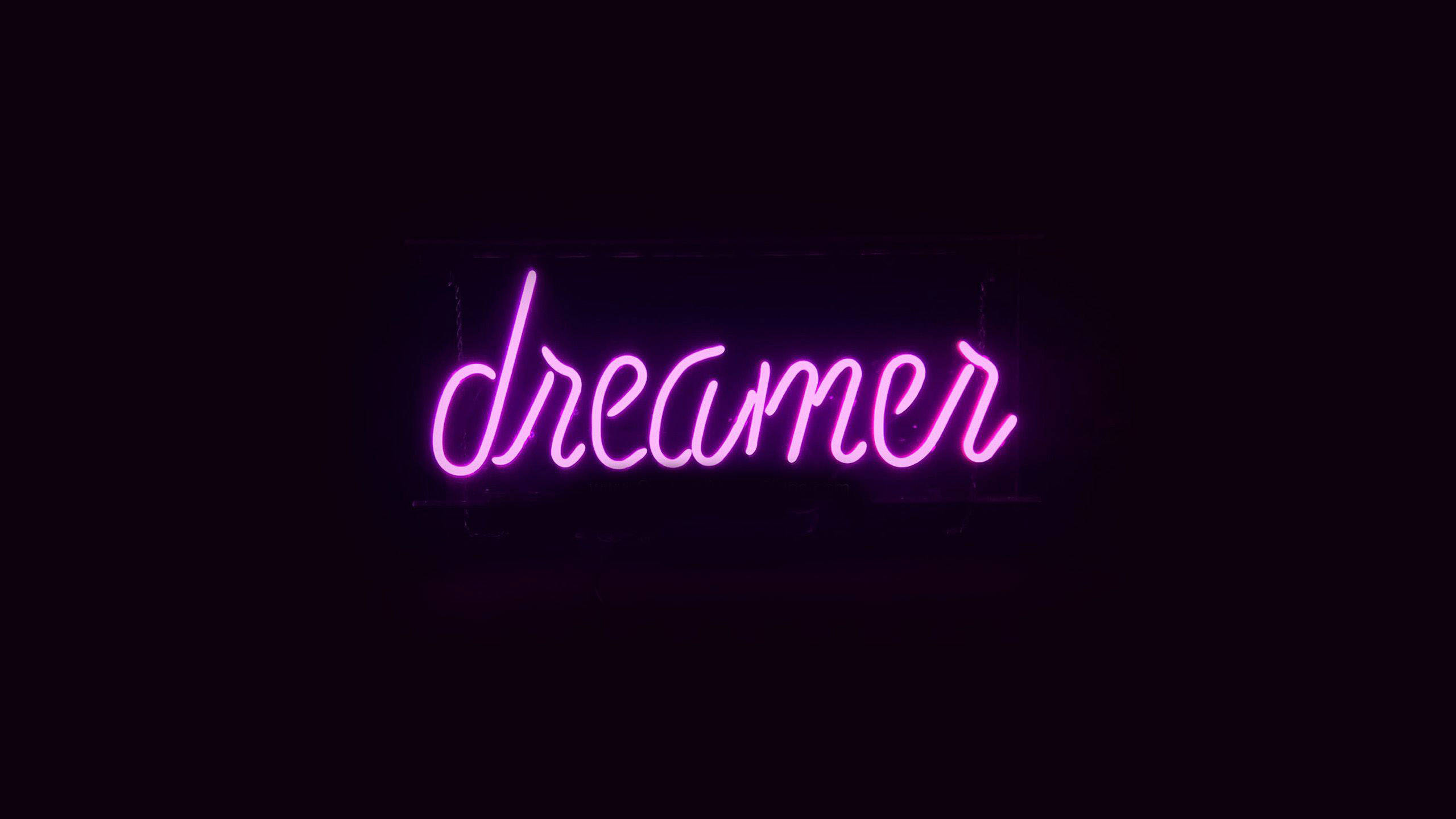 夢幻 桌布 壁紙 — 一個發光的粉紅色霓虹燈牌，拼出dreamer，漂浮在漆黑的背景上。