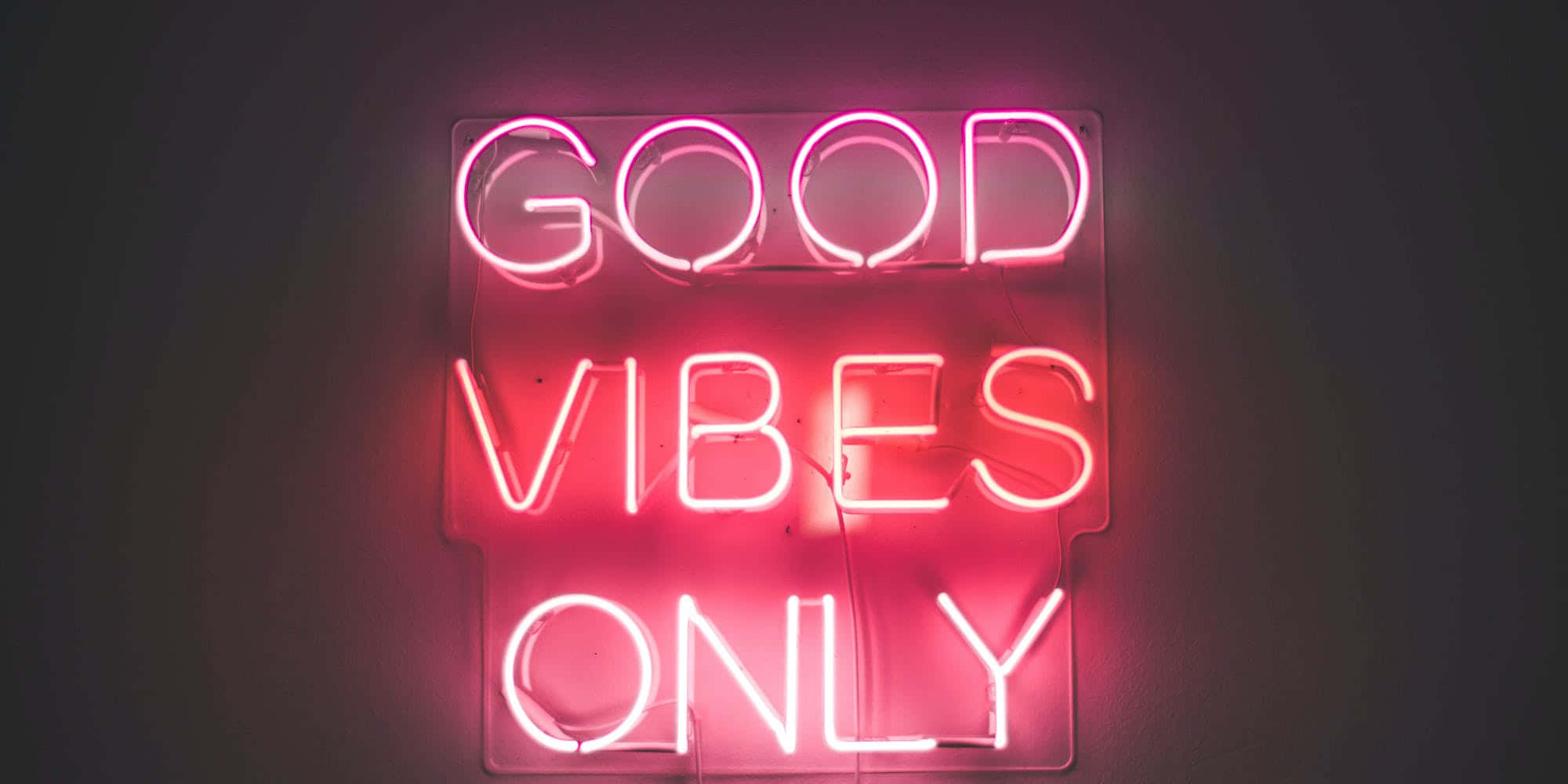 氛圍 桌布 壁紙 — 一個發光的粉紅色霓虹燈牌寫著「GOOD VIBES ONLY」，掛在深色牆上，投射出柔和環境光。