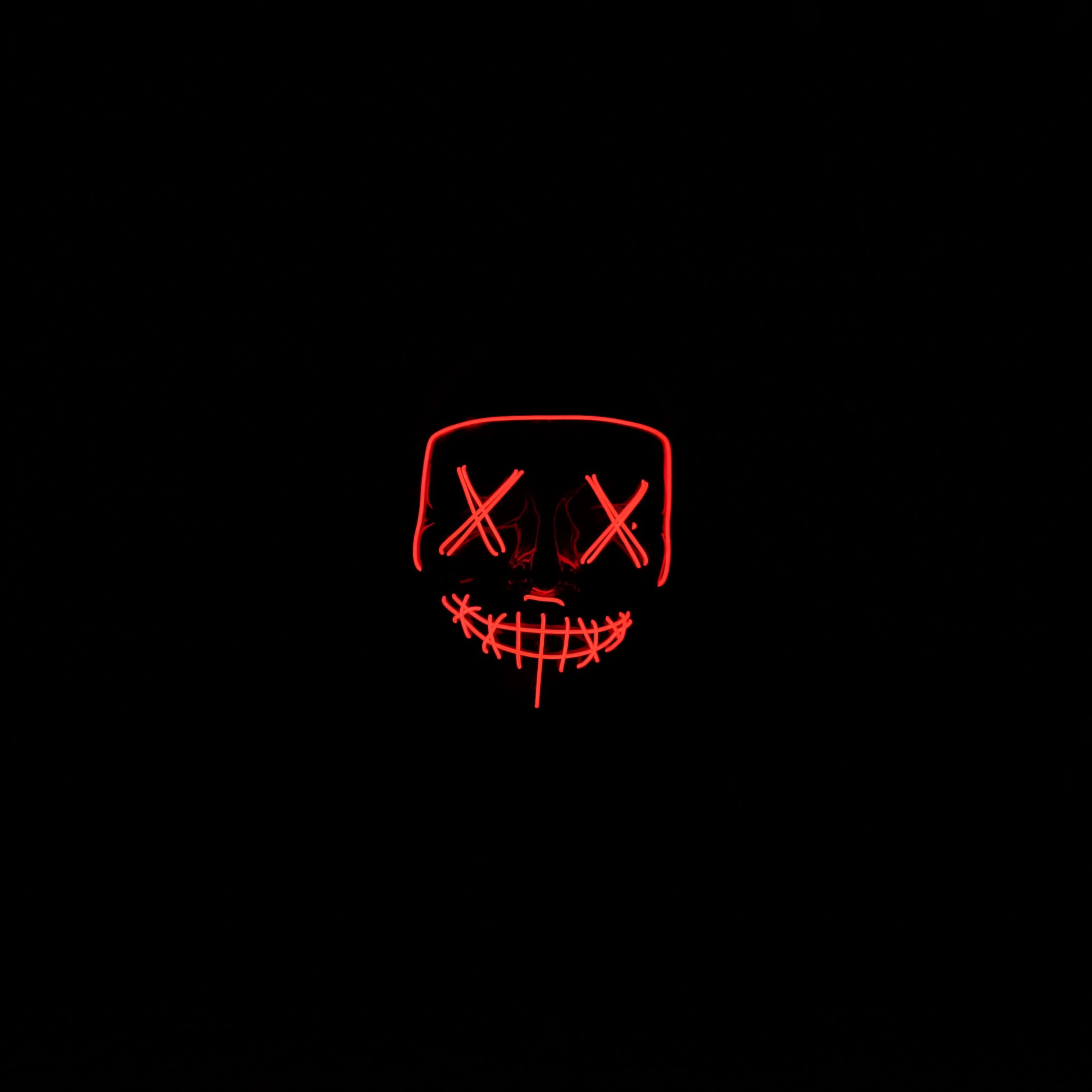 Neon Red Aesthetic 桌布 壁紙 — 一個發光的紅色LED面具，帶有X形眼睛和縫合的笑容，在漆黑的背景上發光。
