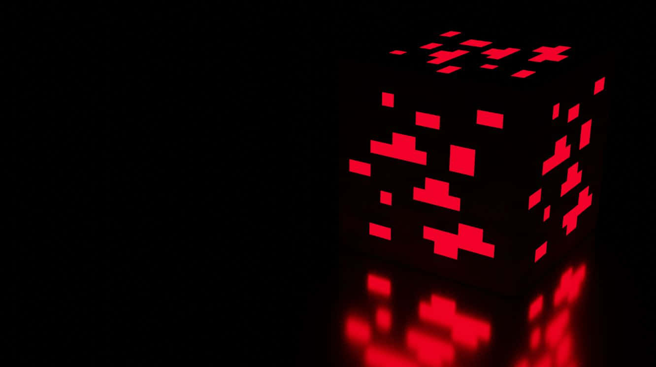 Minecraft Redstone 桌布 壁紙 — 一個發光的紅色像素化立方體在黑色虛空中發出數位心跳，並帶有鏡面反射。