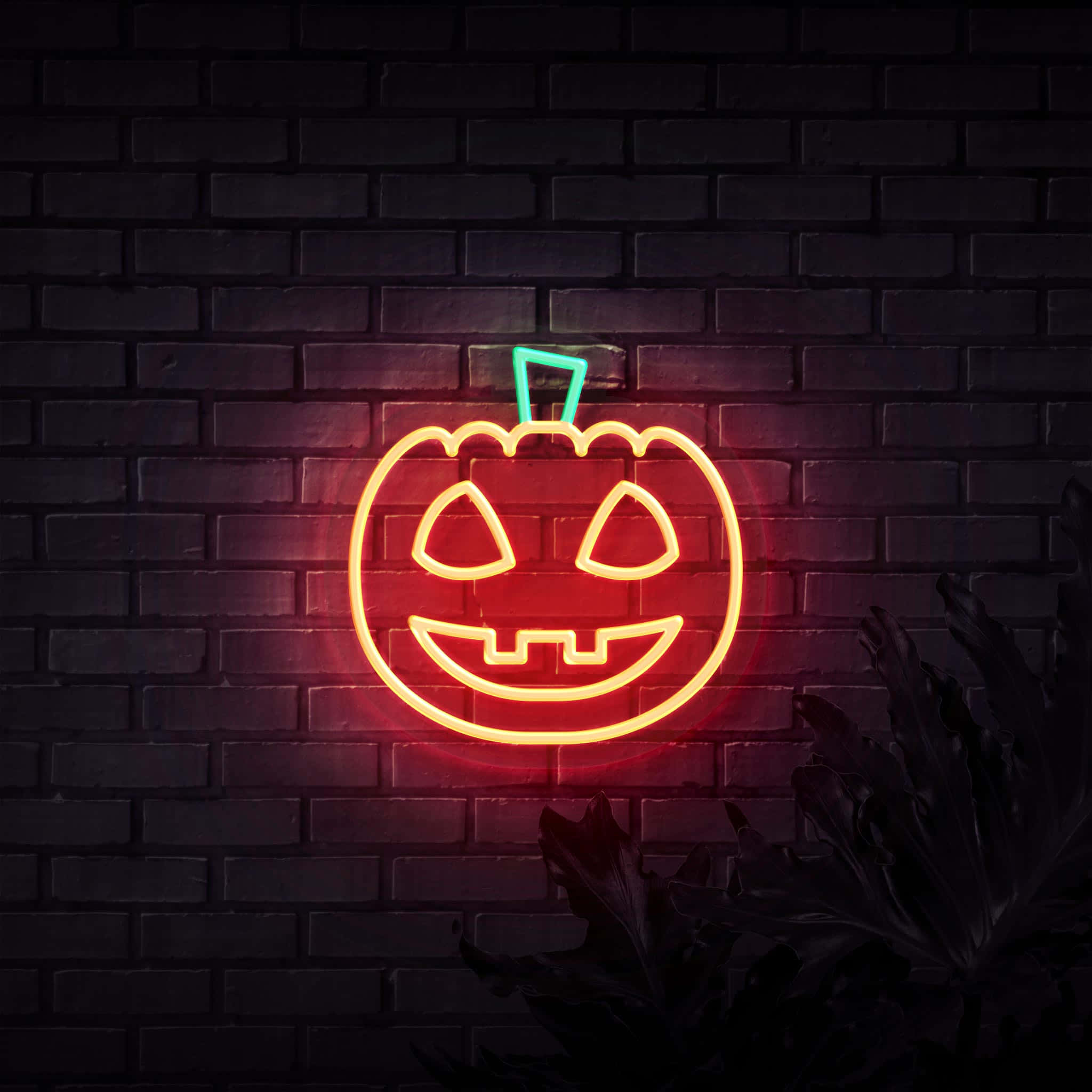 Neon Halloween 桌布 壁紙 — 一個發光的紅色和藍綠色霓虹燈南瓜燈標誌在夜間對著深色磚牆投射出溫暖而詭異的光芒。