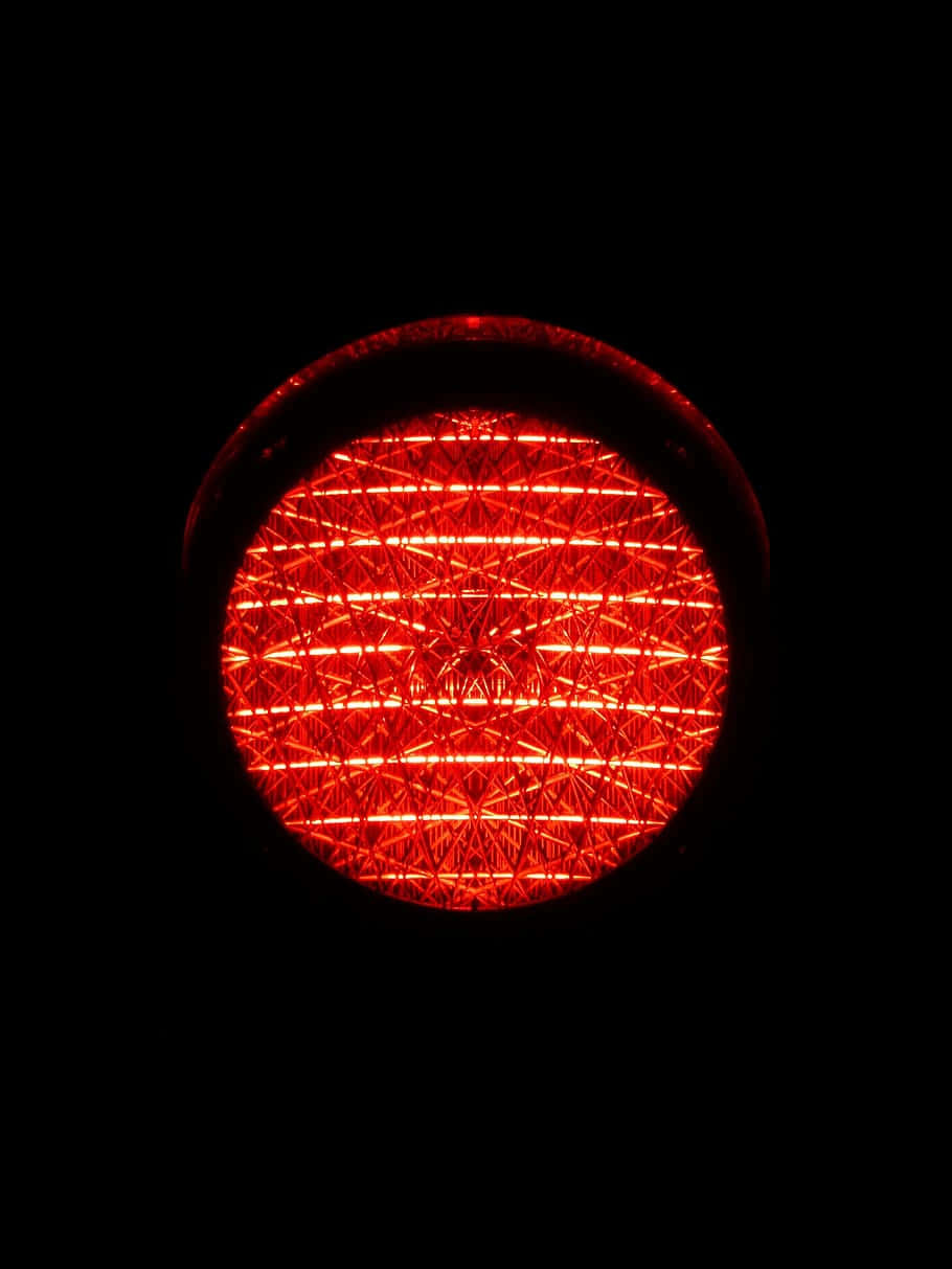 Light 桌布 壁紙 — 一個發光的紅色圓形光，帶有複雜的網格圖案，在漆黑的背景下放射光芒。