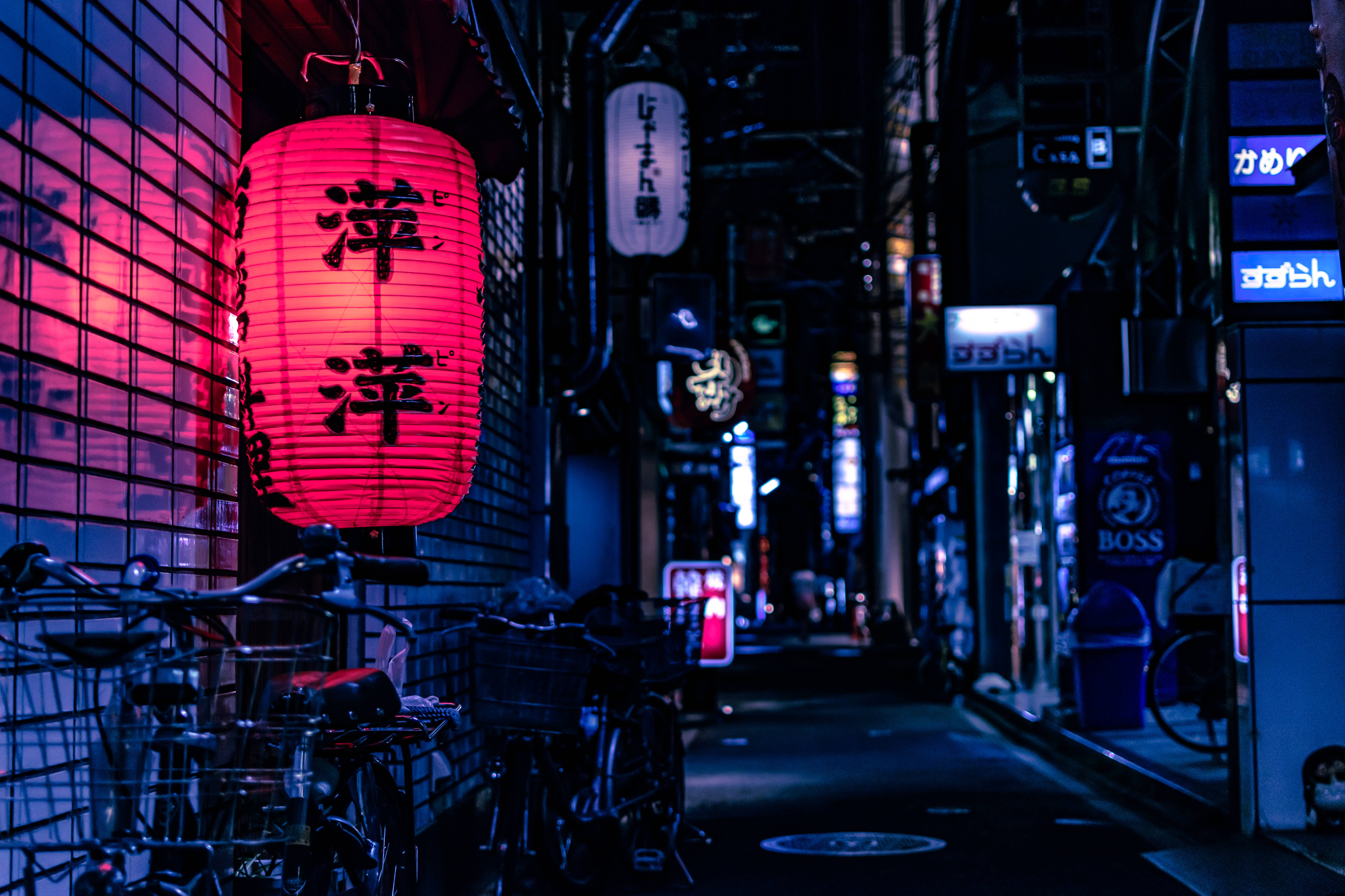動漫 桌布 壁紙 — 一個發光的紅色日本燈籠掛在狹窄的霓虹燈小巷中，夜晚有停放的自行車和發光的標誌。