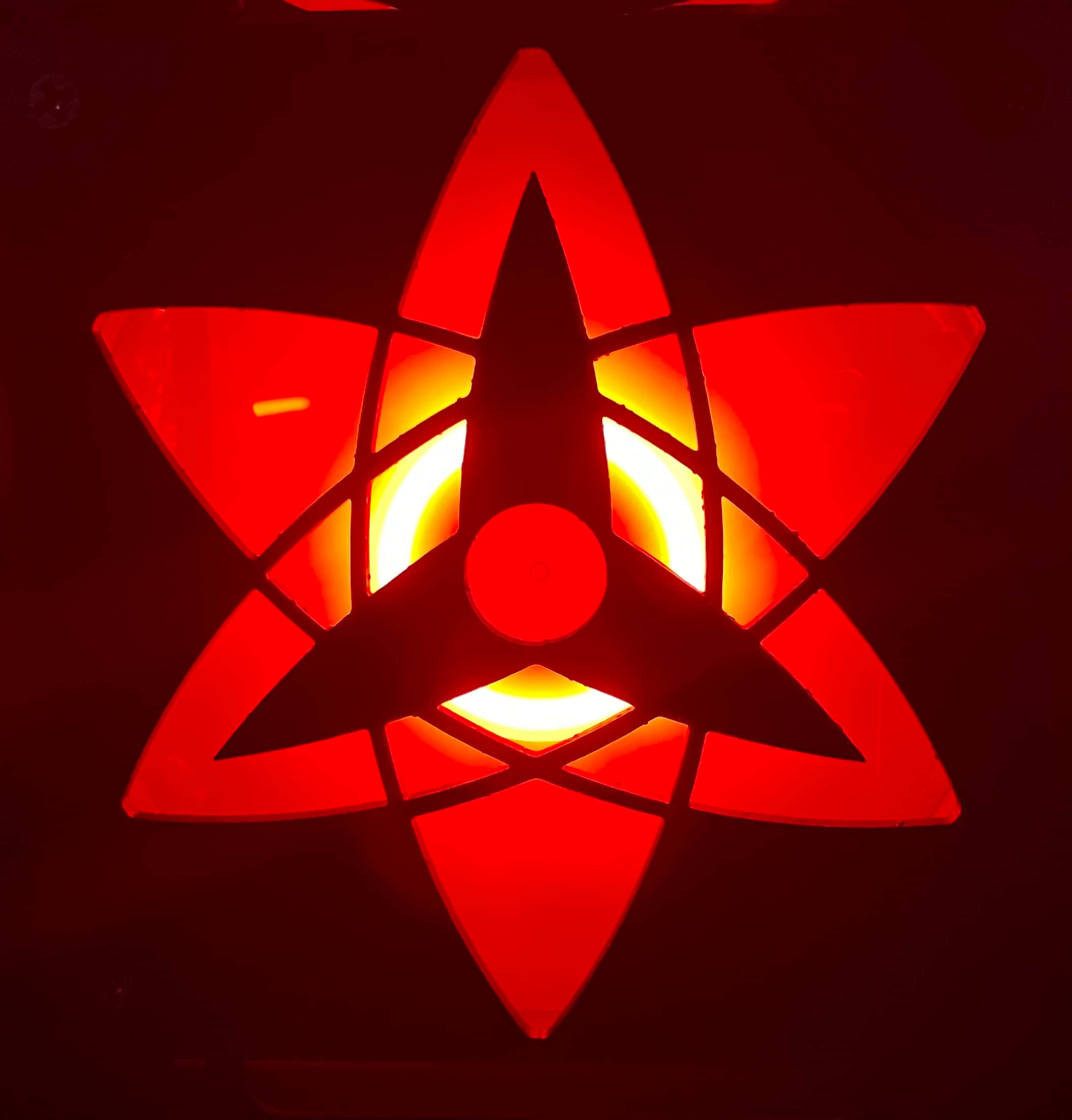 Mangekyou Sharingan 桌布 壁紙 — 一個發光的紅色星形燈籠，帶有溫暖的內部光線，在黑暗背景上投射出銳利的陰影。