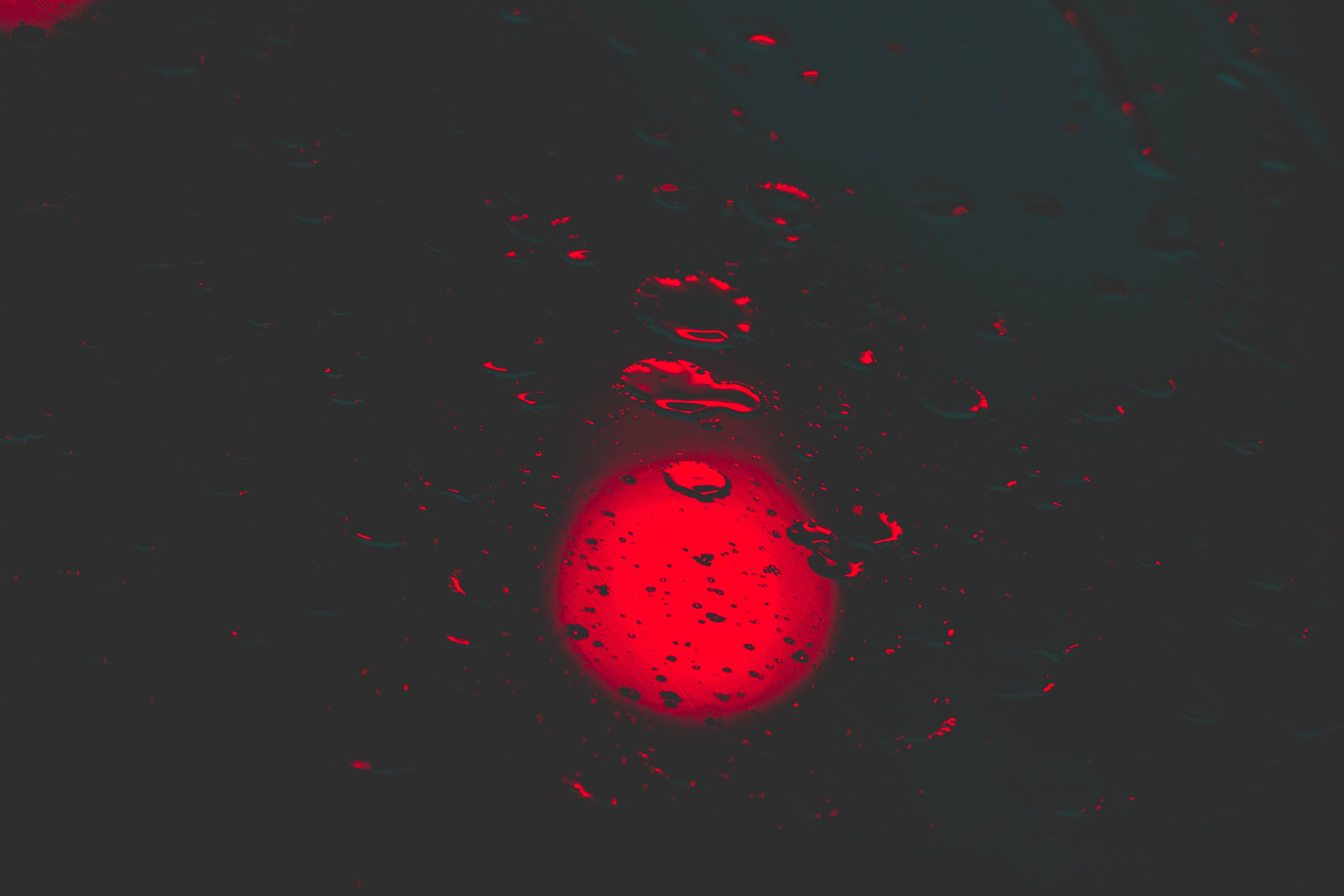 Red Circle 桌布 壁紙 — 一個發光的紅色球體透過黑暗表面上的雨滴觀看，產生扭曲的反射。