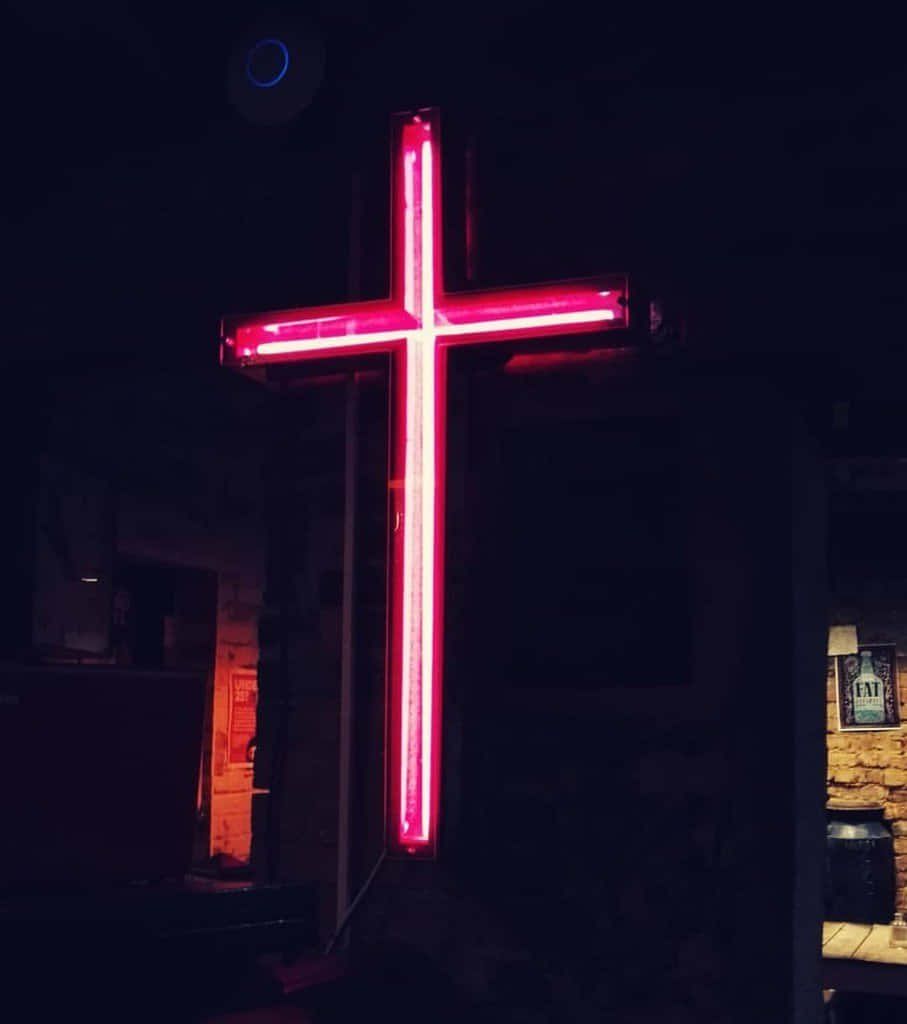 Jesus Saves 桌布 壁紙 — 一個發光的紅色霓虹十字架在昏暗的城市夜景背景下，伴隨著微弱的環境光線，格外突出。