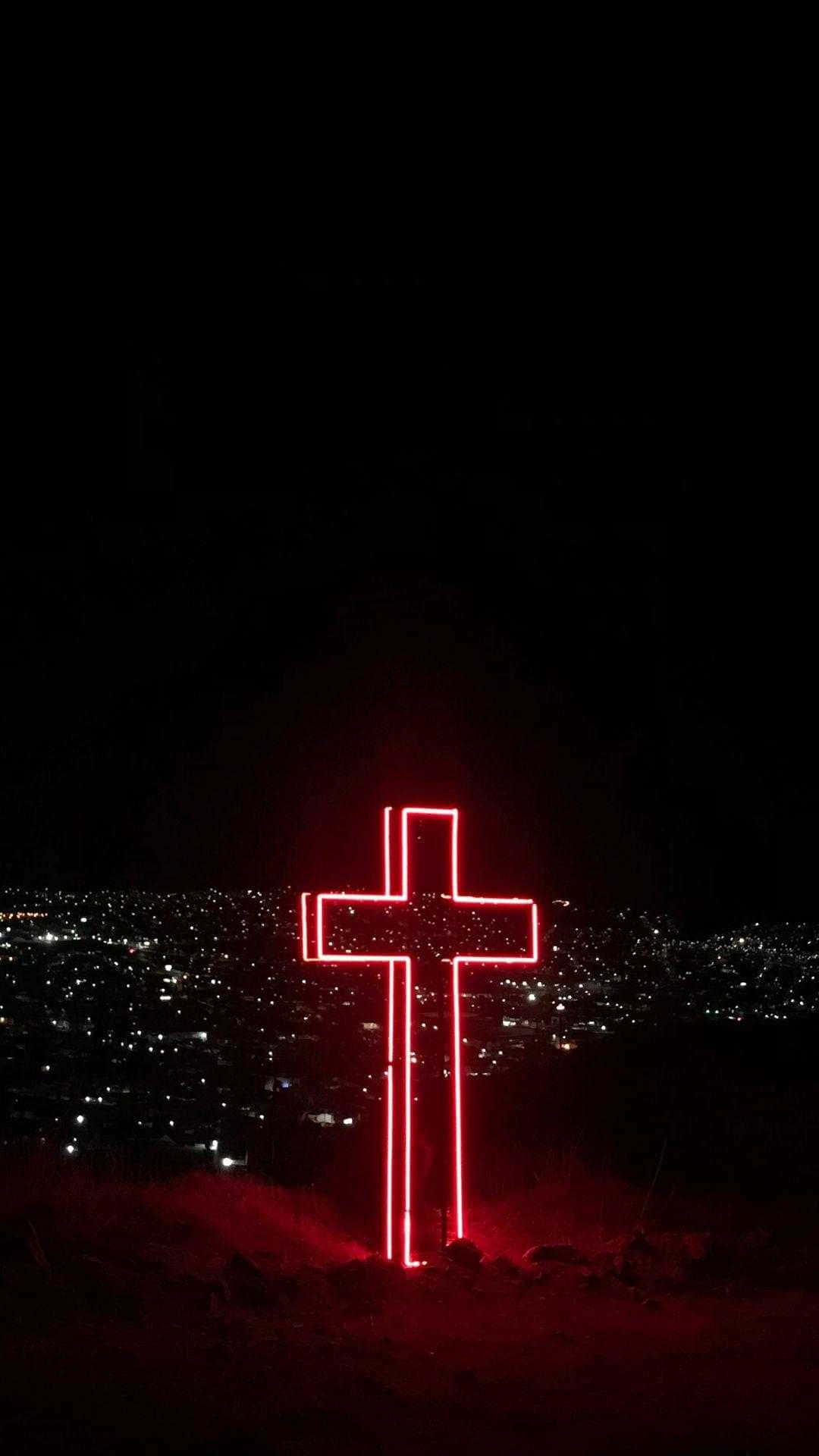 Cool Cross 桌布 壁紙 — 一個發光的紅色霓虹十字架矗立在山頂上，俯瞰著夜晚被無數閃爍燈光照亮的廣闊城市景觀。