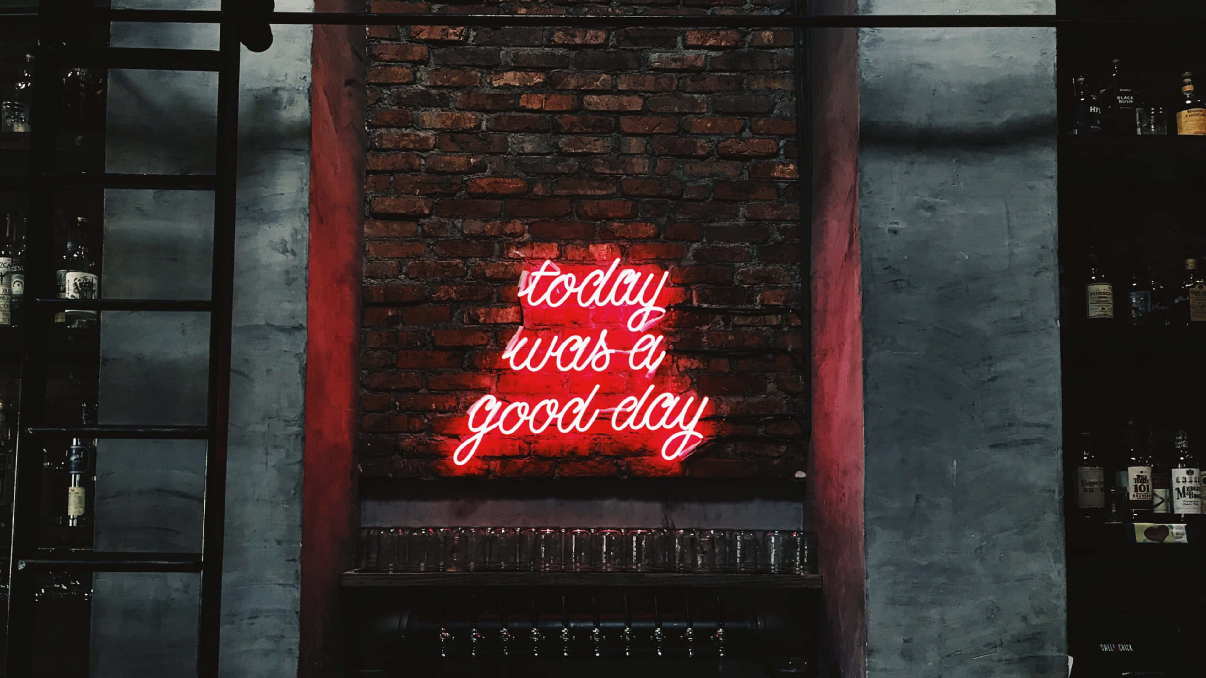 桌布 壁紙 — 一個發光的紅色霓虹燈牌，上面寫著「today was a good day」，照亮了酒吧後面的磚牆，牆上有玻璃器皿和酒瓶。