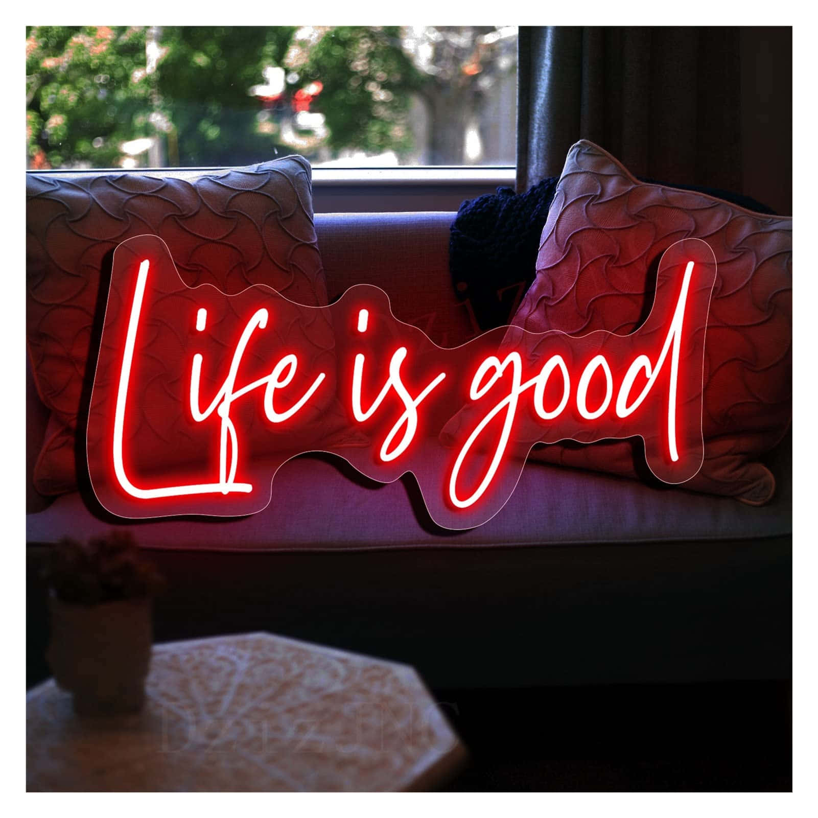 Life Is Good 桌布 壁紙 — 一個發光的紅色霓虹燈牌，上面寫著「Life is good」，放在窗邊一張有紋理枕頭的沙發上。