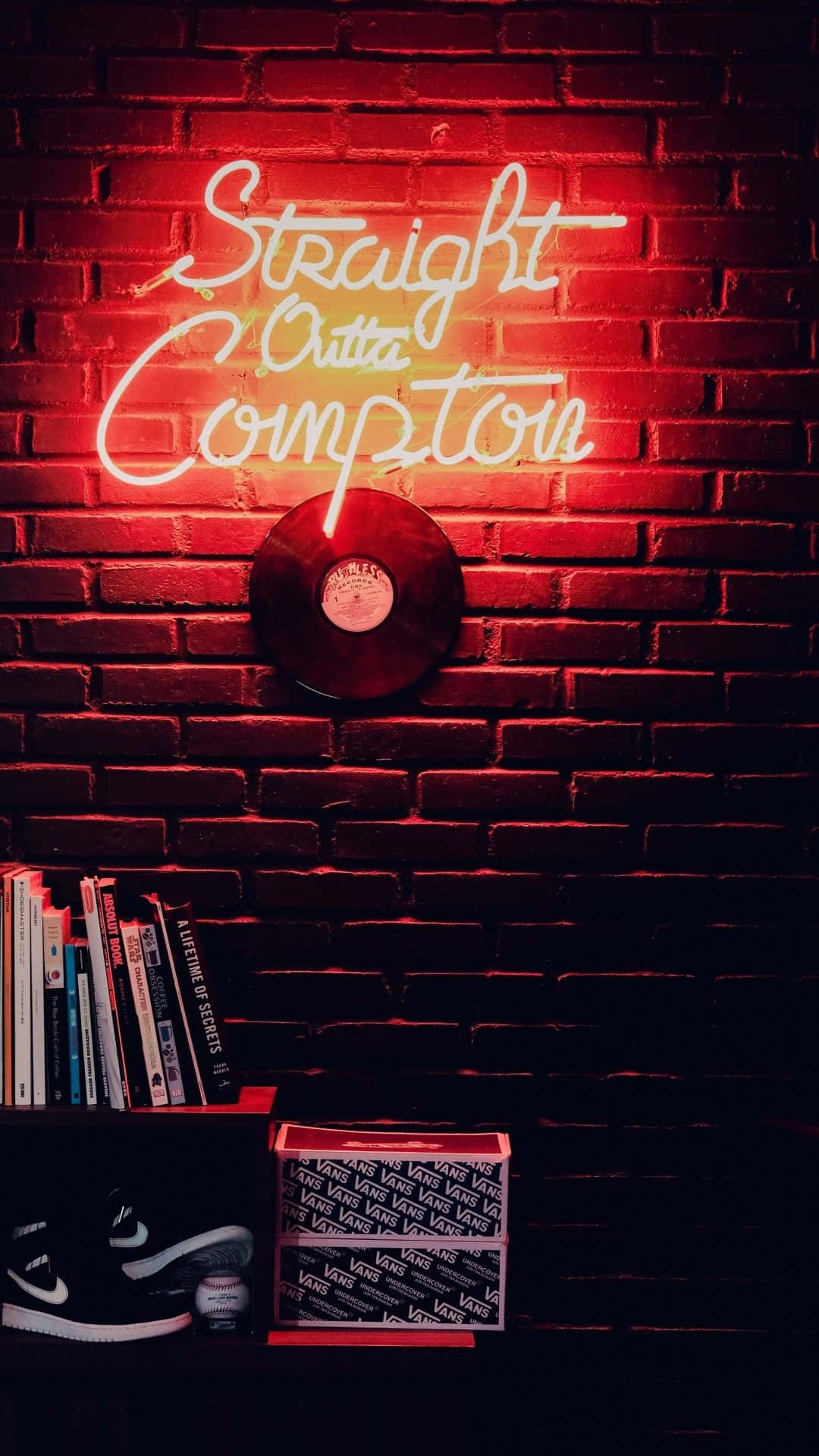 音樂 桌布 壁紙 — 一個發光的紅色霓虹燈牌，上面寫著「Straight Outta Compton」，照亮了磚牆，牆上放著黑膠唱片、書本和運動鞋的架子。