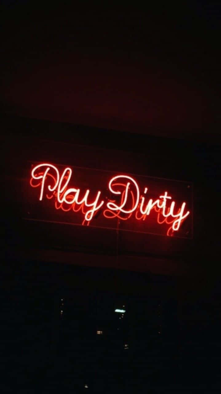 Neon Light 桌布 壁紙 — 一個發光的紅色霓虹燈牌，上面寫著 Play Dirty，照亮了黑暗的城市夜景。
