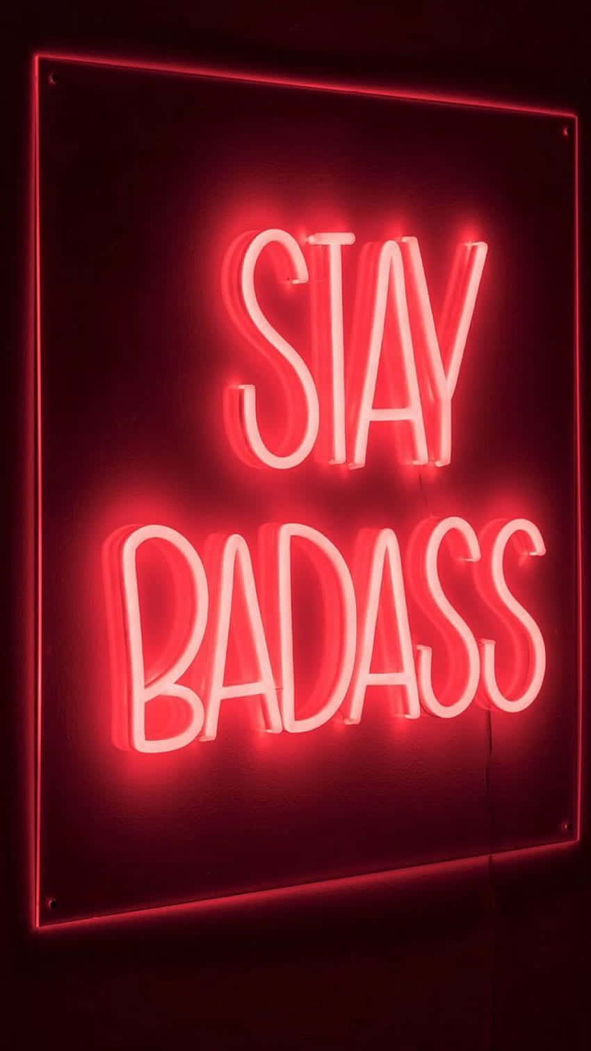 Neon Red Aesthetic 桌布 壁紙 — 一個發光的紅色霓虹燈牌，上面用粗體草書寫著「STAY BADASS」，背景是深色牆壁。