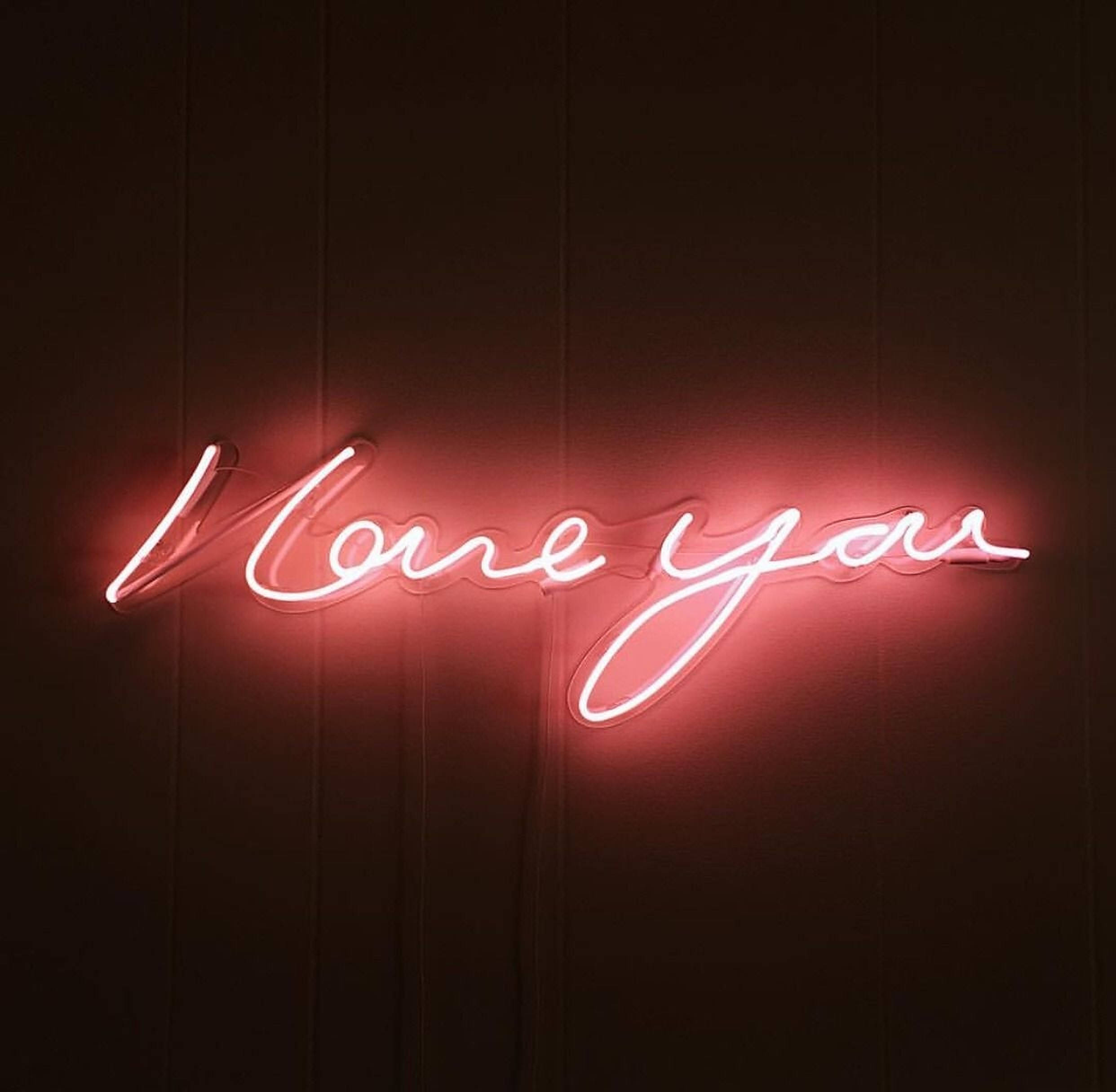 我愛你 桌布 壁紙 — 一個發光的紅色霓虹燈牌，以草書拼出「Love you」，背景為深色木牆。