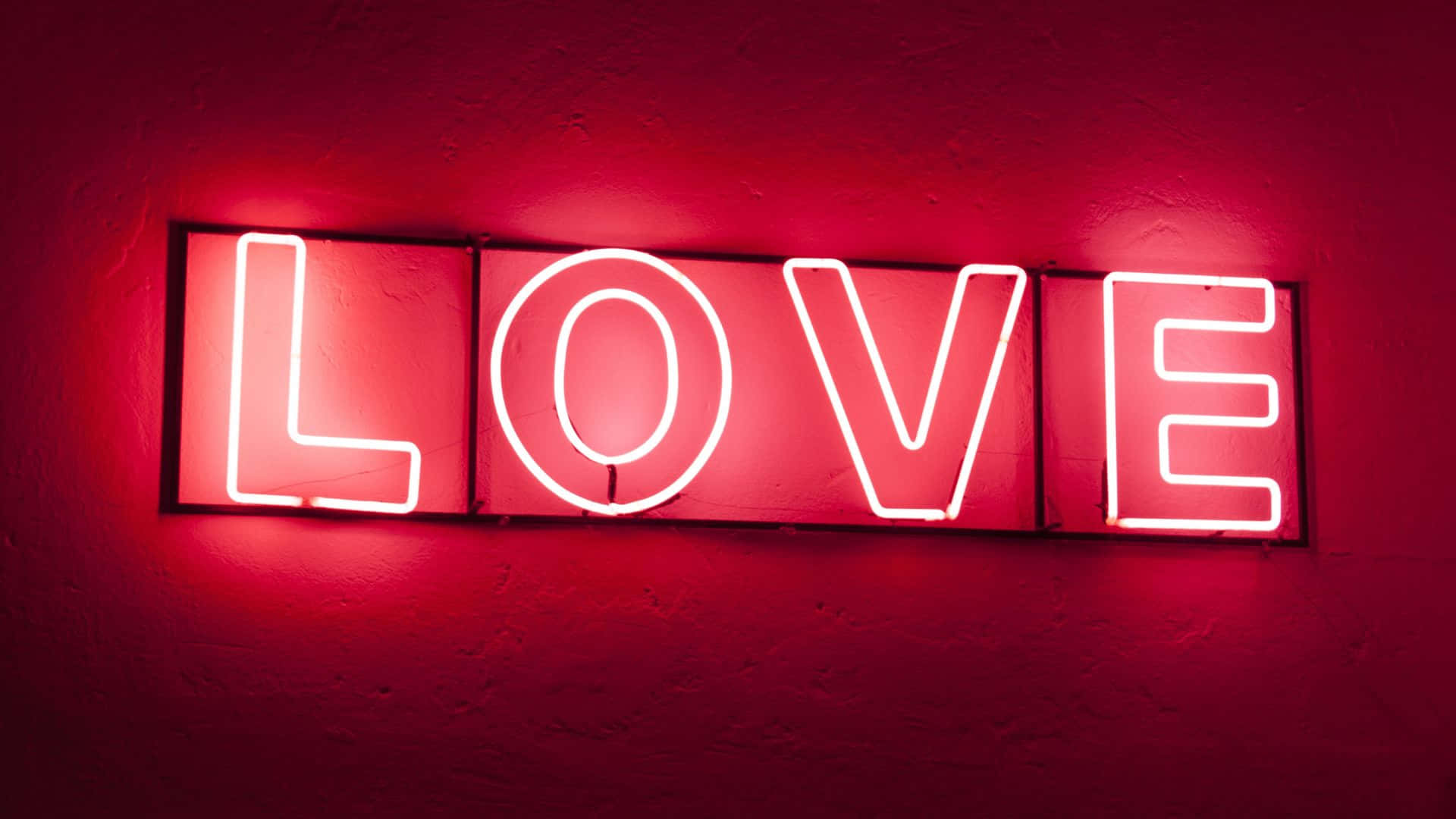 Beautiful Love 桌布 壁紙 — 一個發光的紅色霓虹燈牌，拼出LOVE，在紋理牆壁上投射出溫暖的光芒。