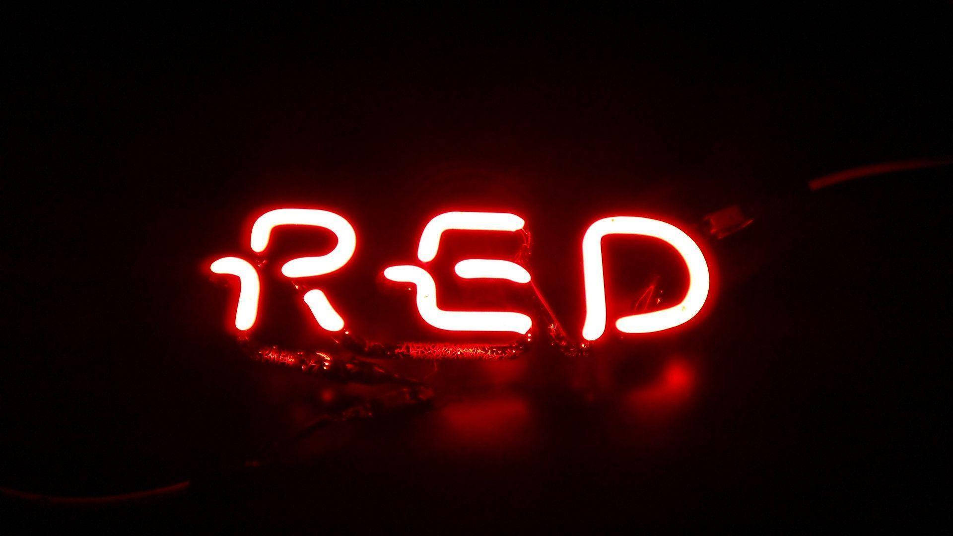 紅色動圖 桌布 壁紙 — 一個發光的紅色霓虹燈牌，拼寫著「RED」，在漆黑的背景下明亮地閃耀。
