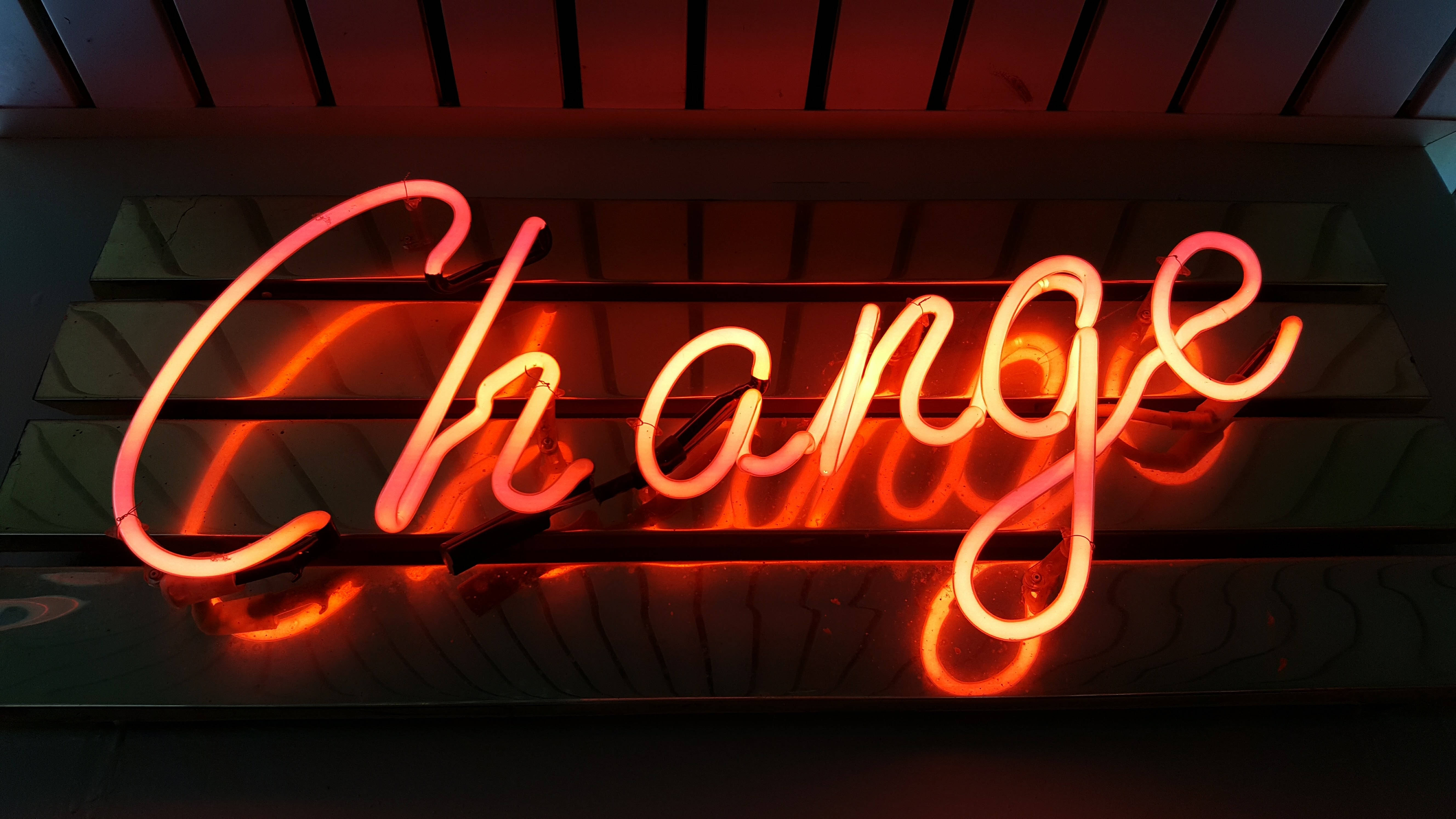 Random 桌布 壁紙 — 一個發光的紅色霓虹燈牌，拼寫著「Change」，在深色木條牆上投射出溫暖的光芒。