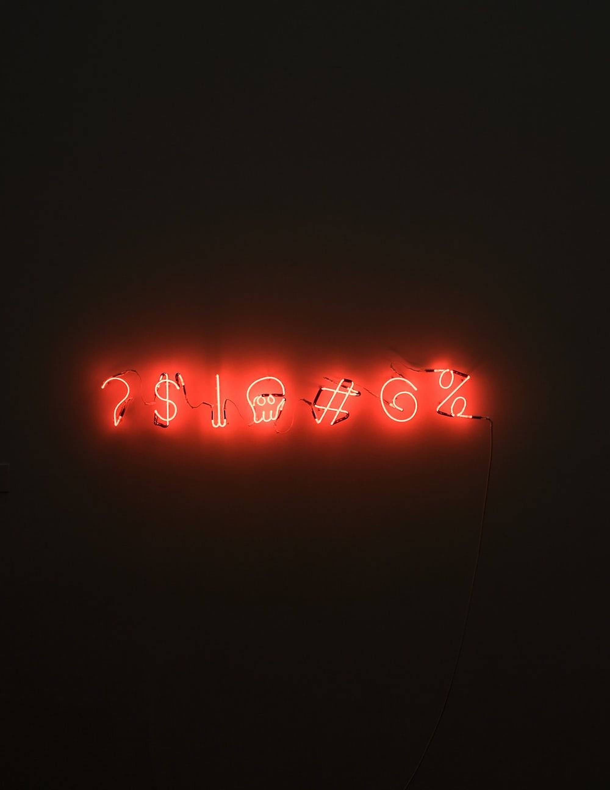 LED 桌布 壁紙 — 一個發光的紅色霓虹燈牌在暗牆上顯示符號，包括問號、美元、骷髏和百分號。