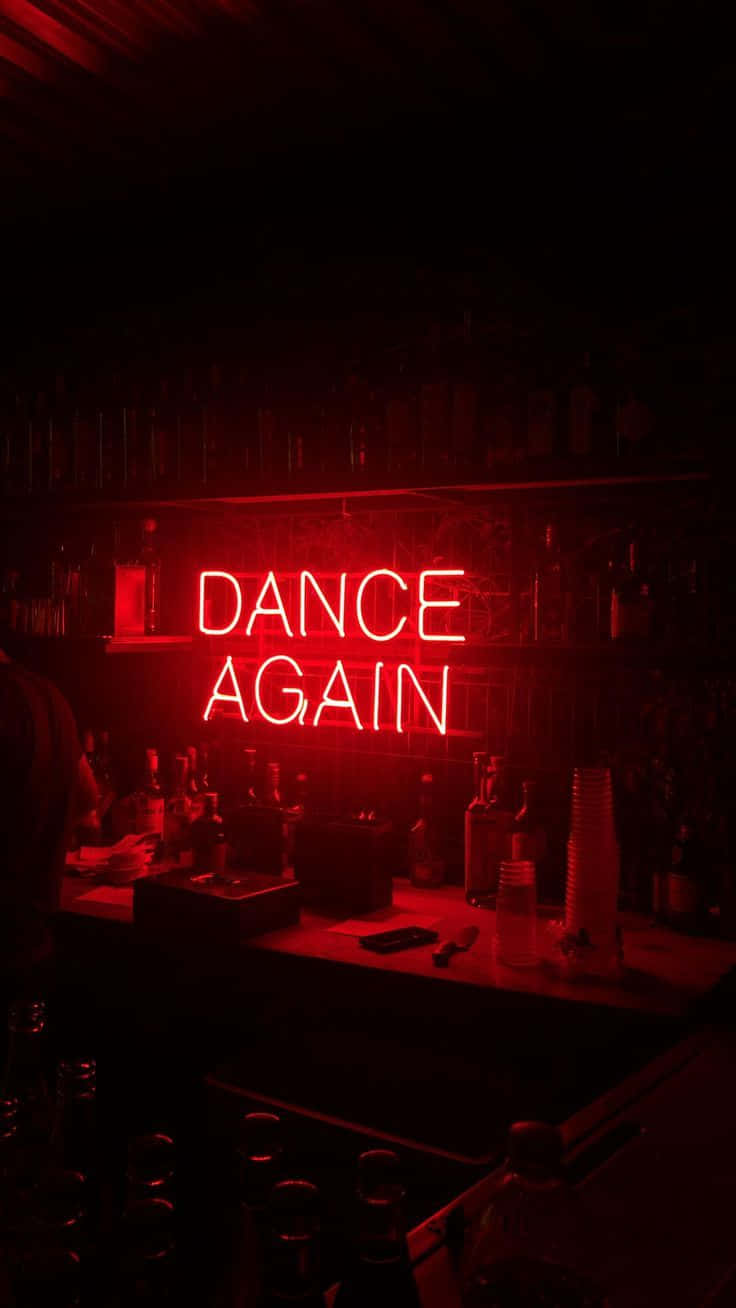 語錄 桌布 壁紙 — 一個發光的紅色霓虹燈牌寫著 dance again，照亮了一個光線昏暗、擺滿酒瓶和酒杯的吧檯。