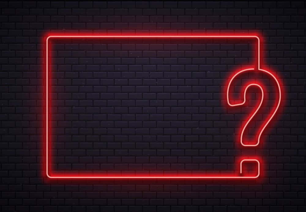 Question Mark 桌布 壁紙 — 一個發光的紅色霓虹矩形和問號照亮了黑暗的磚牆，帶有現代都市氛圍。