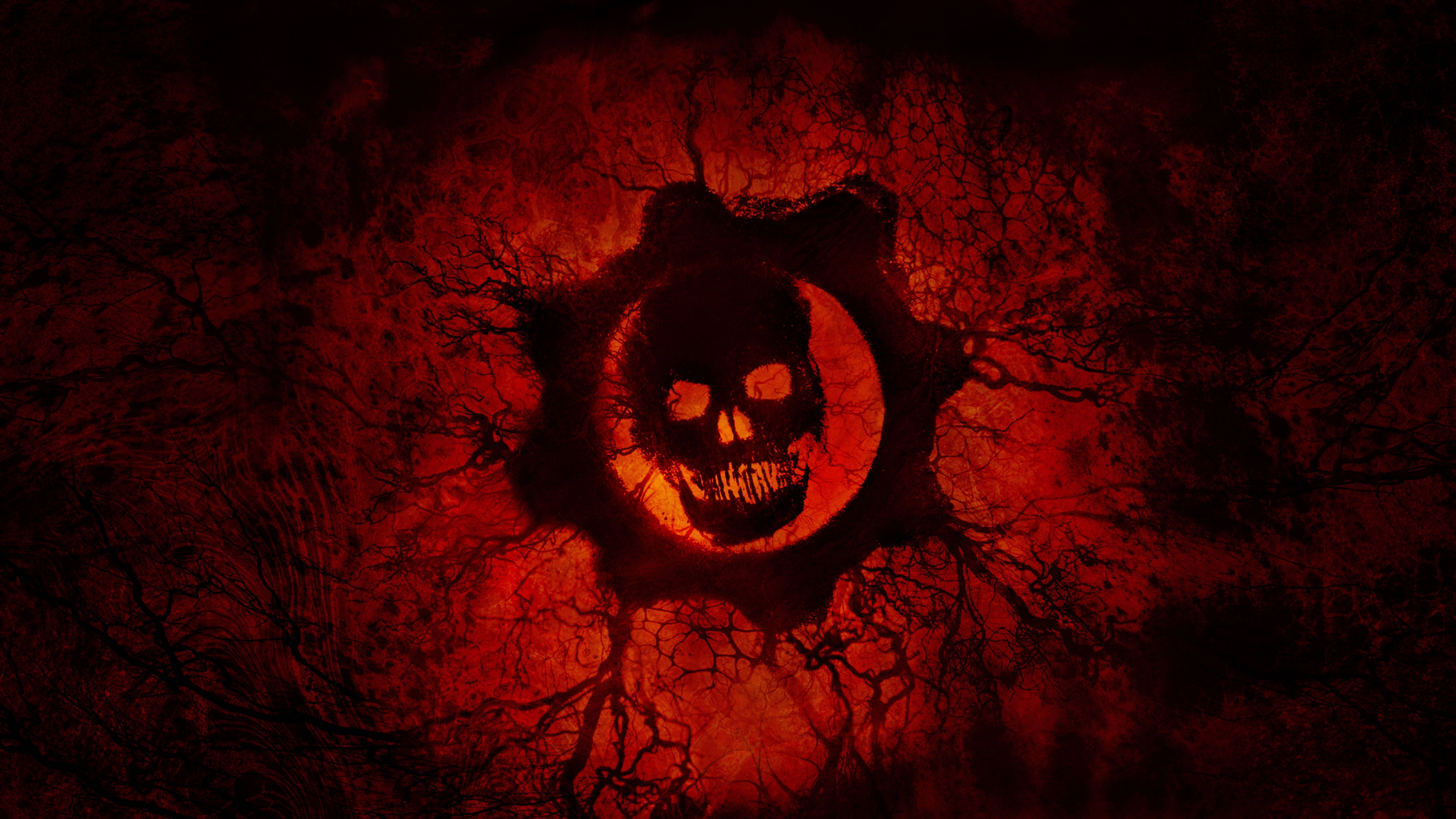 Gears Of War 桌布 壁紙 — 一個發光的紅色骷髏頭，帶有鋸齒狀牙齒，從一個破裂的、熾熱的表面出現，周圍環繞著黑暗、扭曲的樹枝。