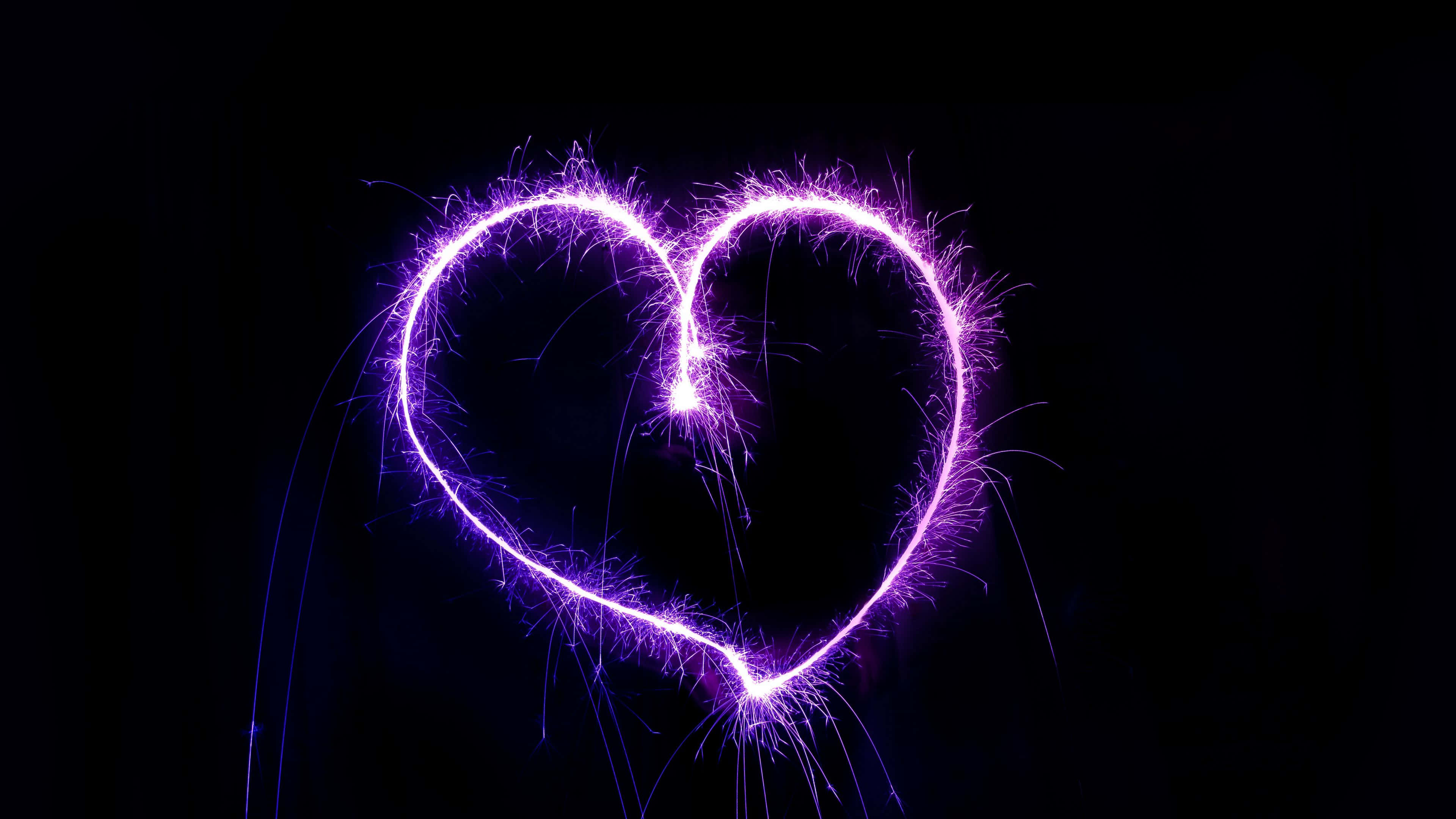 4K Love 桌布 壁紙 — 一個發光的紫色心形煙火在漆黑背景中爆發出電光。