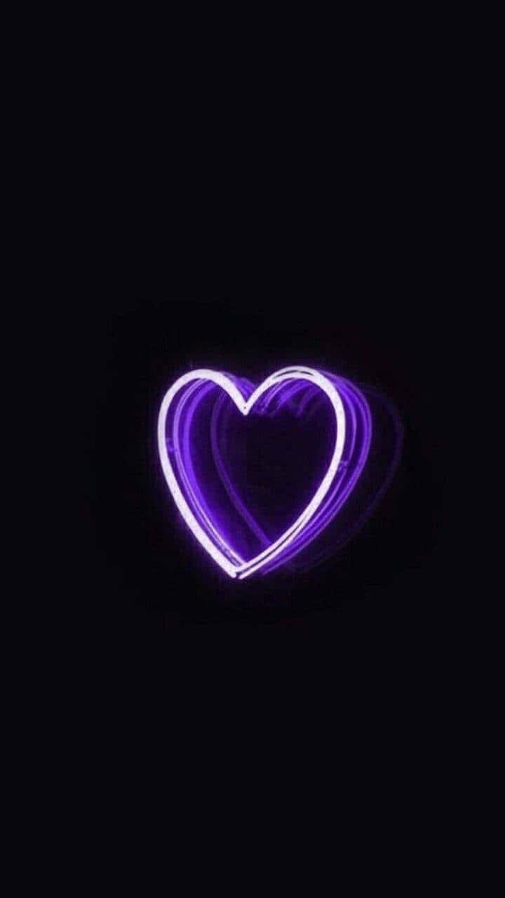 Neon Aesthetic Phone 桌布 壁紙 — 一個發光的紫色霓虹心臟在漆黑的背景上閃耀著明亮的光芒。