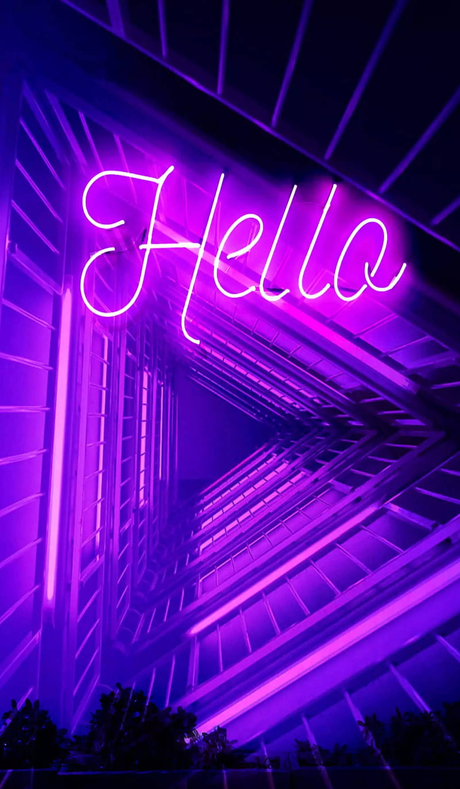 LED 桌布 壁紙 — 一個發光的紫色霓虹燈牌，拼出「Hello」，照亮了夜晚中幾何圖案的城市小巷。
