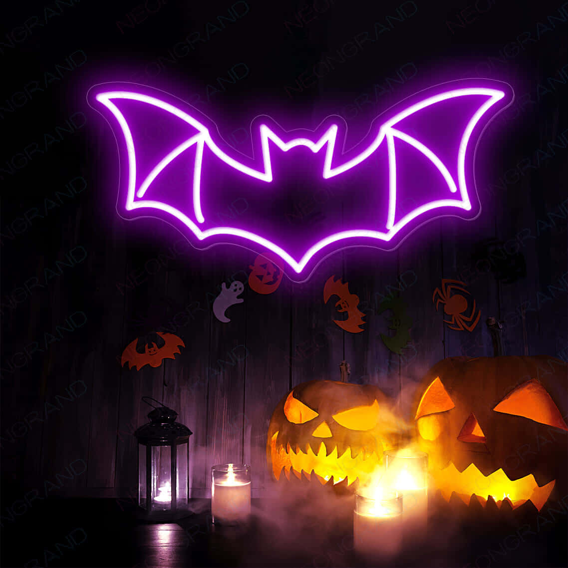 Neon Halloween 桌布 壁紙 — 一個發光的紫色霓虹蝙蝠標誌懸浮在雕刻的南瓜燈和閃爍的蠟燭上方，營造出詭異的萬聖節場景。