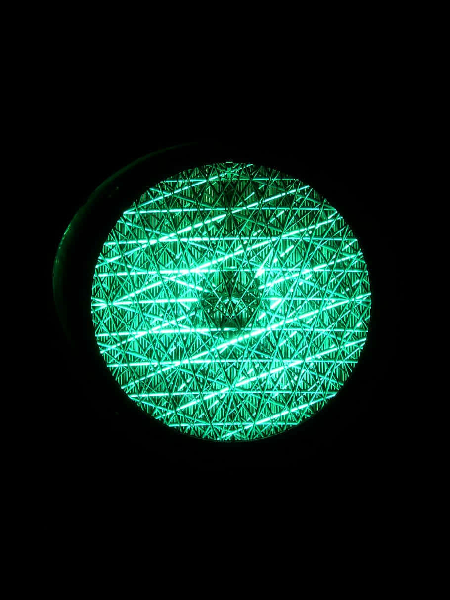 Light 桌布 壁紙 — 一個發光的綠色圓形圖案，帶有交叉線條，在黑色背景上放射光芒。