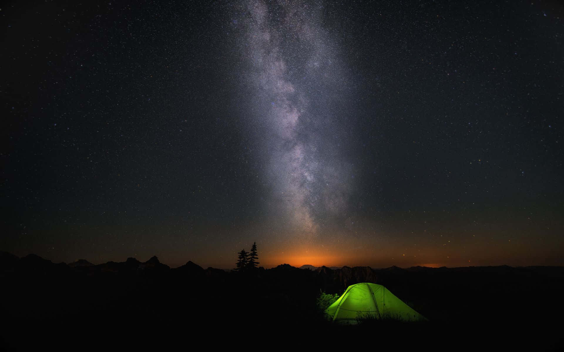 Stars 桌布 壁紙 — 一個發光的綠色帳篷坐落在令人驚嘆的銀河系下，銀河在夜晚彎曲在黑暗的山脈上。