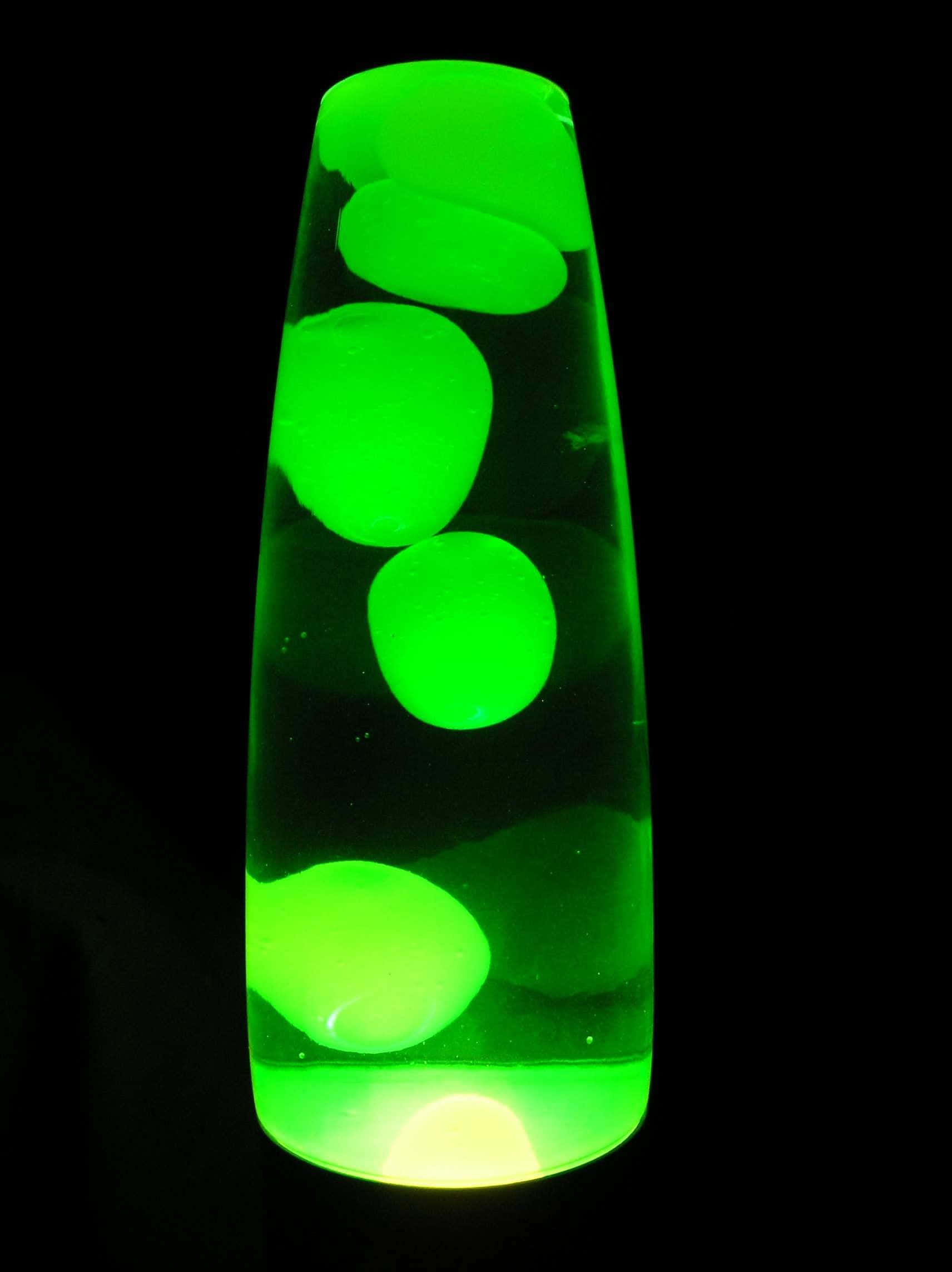 lava lamp 桌布 壁紙 — 一個發光的綠色熔岩燈，在黑色背景下的深色液體中浮起氣泡。