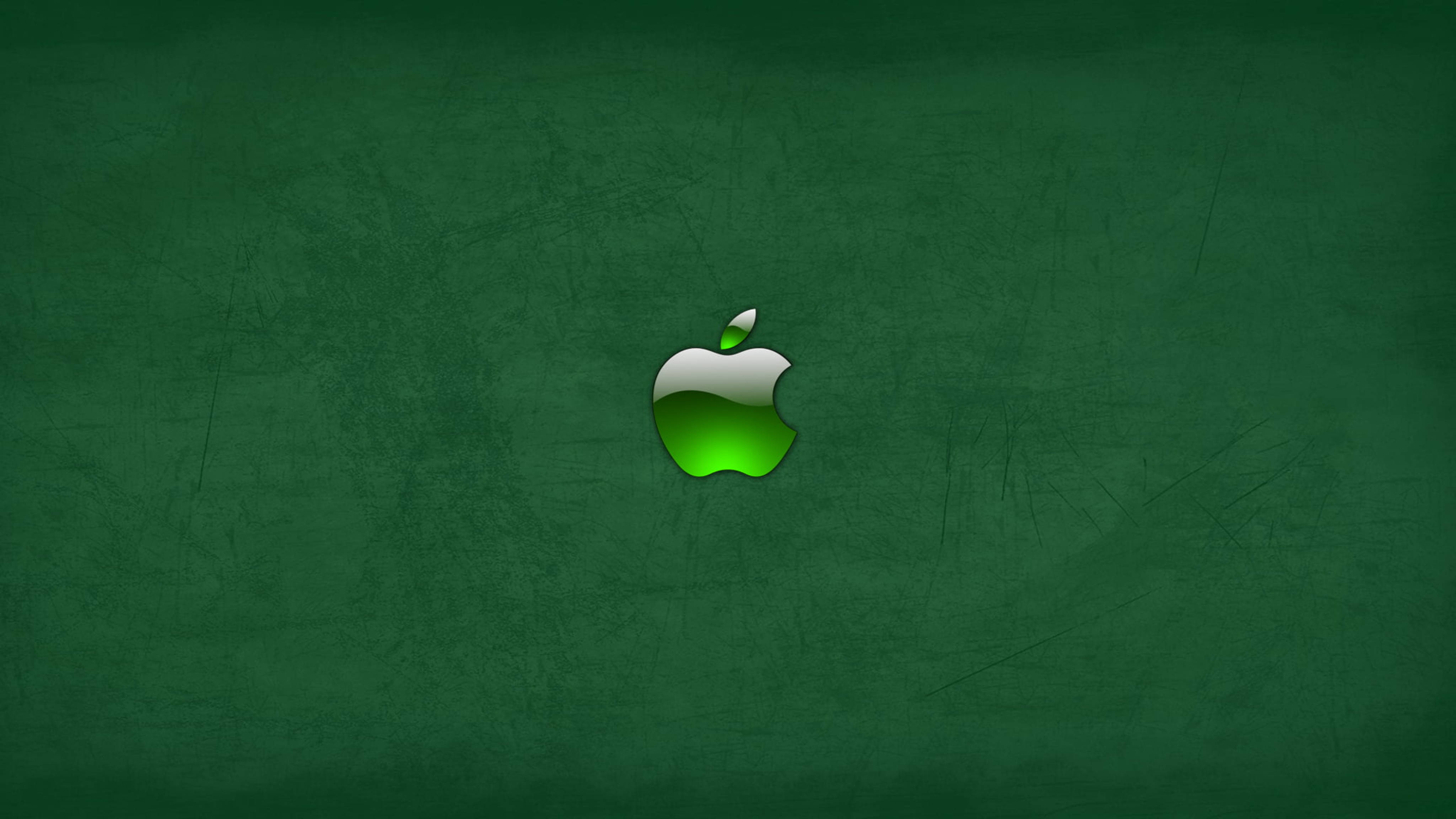 Apple 4K Ultra HD 桌布 壁紙 — 一個發光的綠色蘋果標誌，居中在帶有紋理的深綠色黑板背景上。