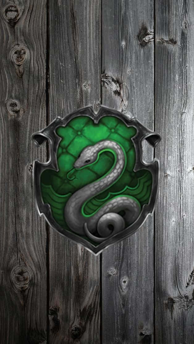 Cute Slytherin 桌布 壁紙 — 一個發光的綠色蛇形徽章，位於風化的灰色木牆上，可見木紋和節疤。