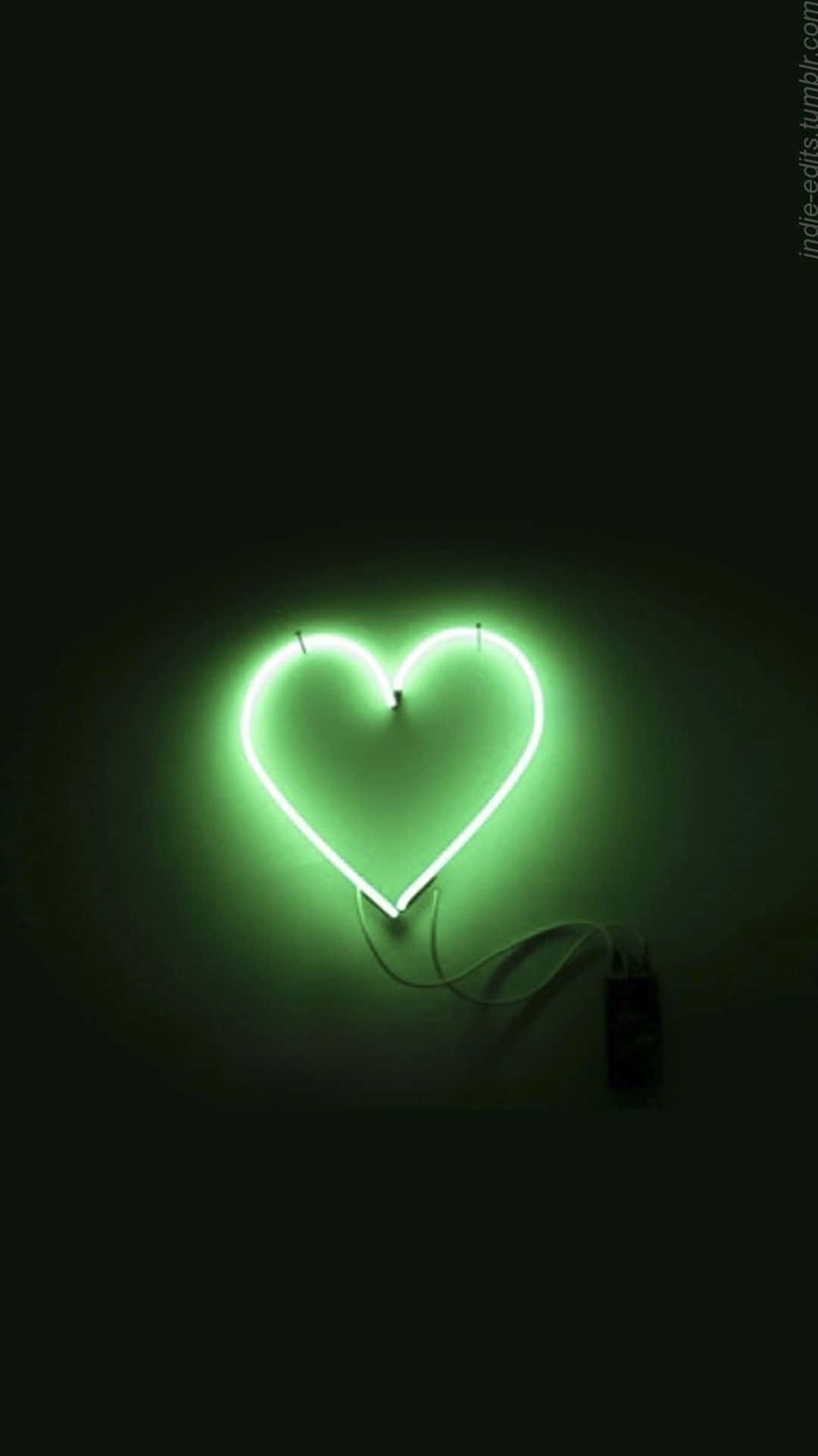 Green Led 桌布 壁紙 — 一個發光的綠色霓虹心形標誌在簡約環境中，對著深色牆壁投射出柔和的光線。